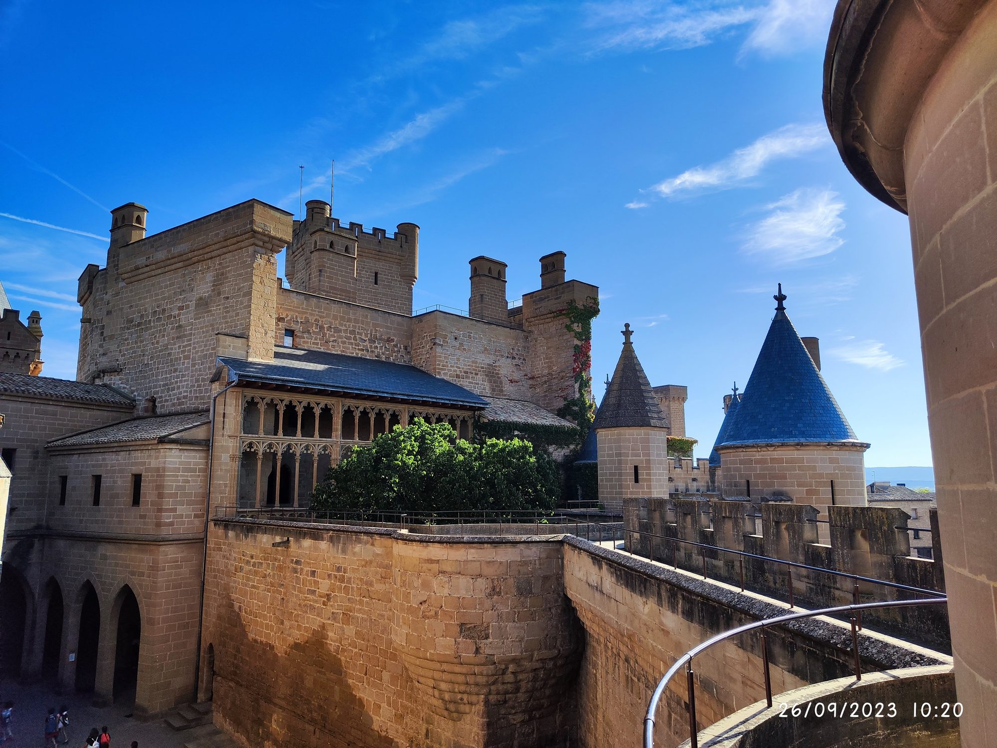 Torres de piedra y galerías góticas del Palacio Real de Olite bajo el cielo azul.