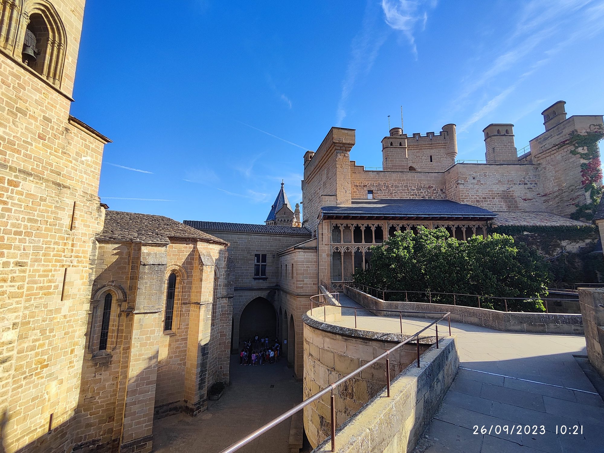 Castillo medieval de Olite con torres de piedra y pasarelas bajo un cielo azul.