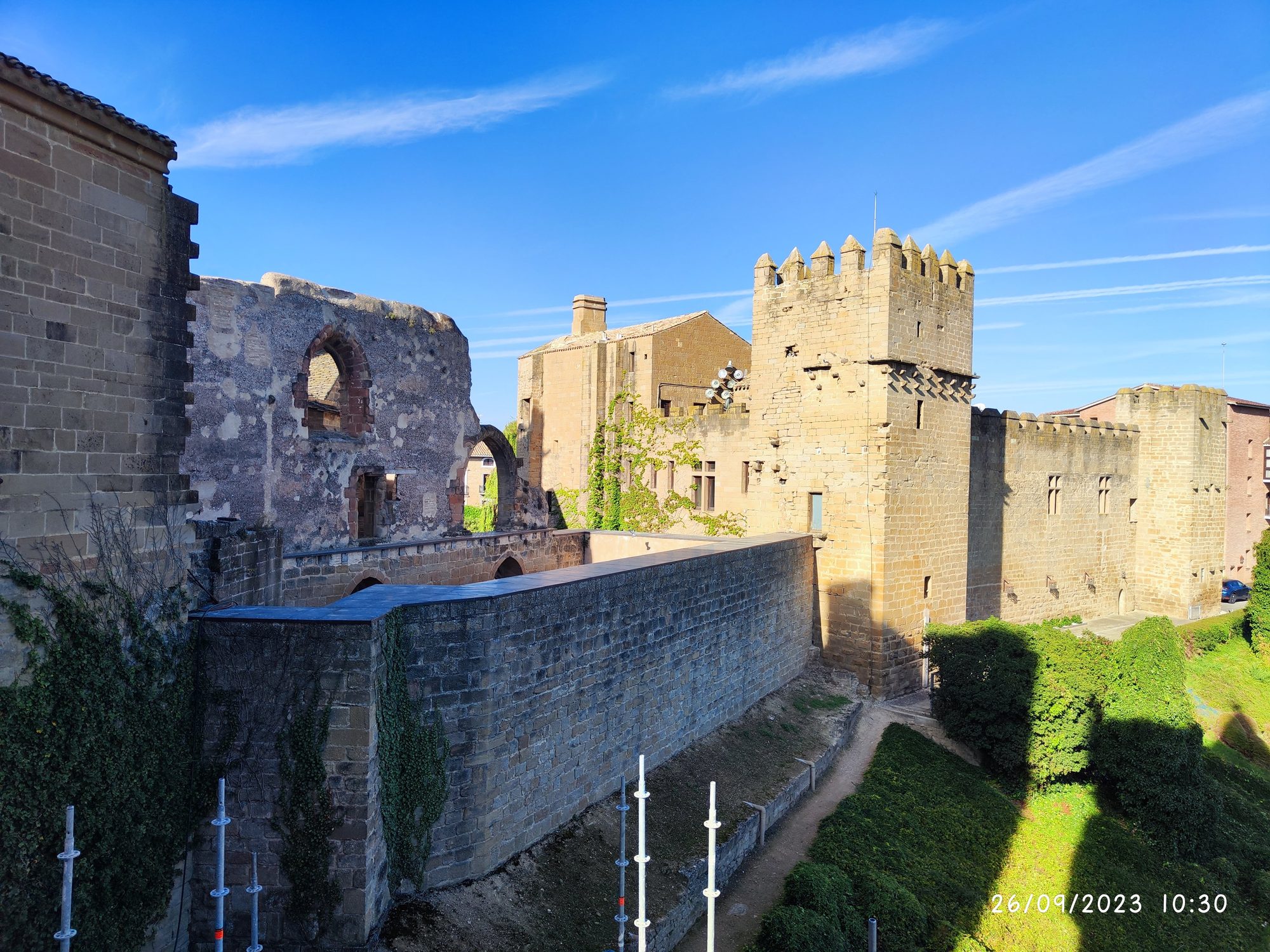 Muros de piedra y torres del castillo medieval de Olite bajo un cielo azul soleado.