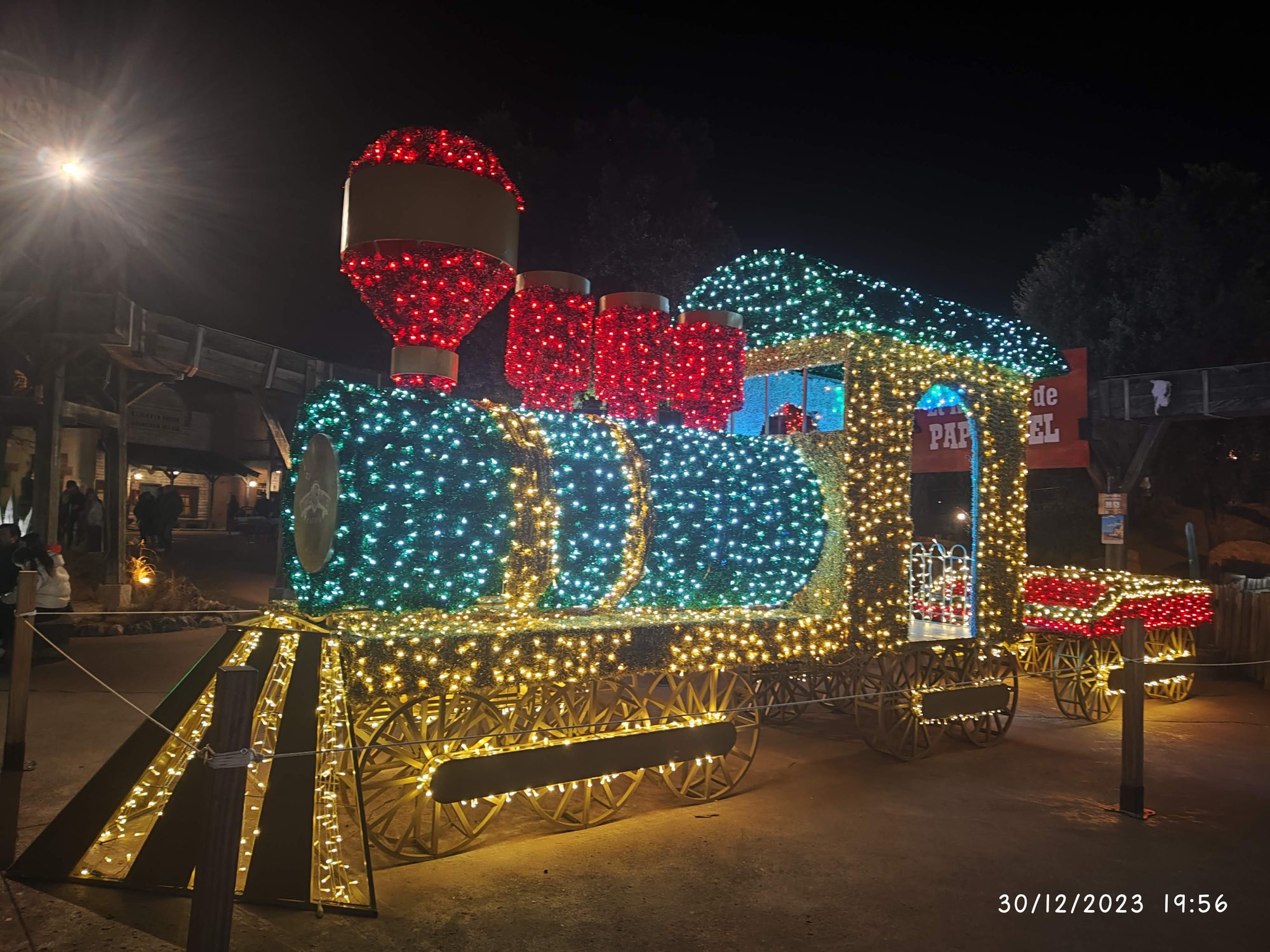 Escultura de un tren decorada con luces navideñas de colores brillantes por la noche.