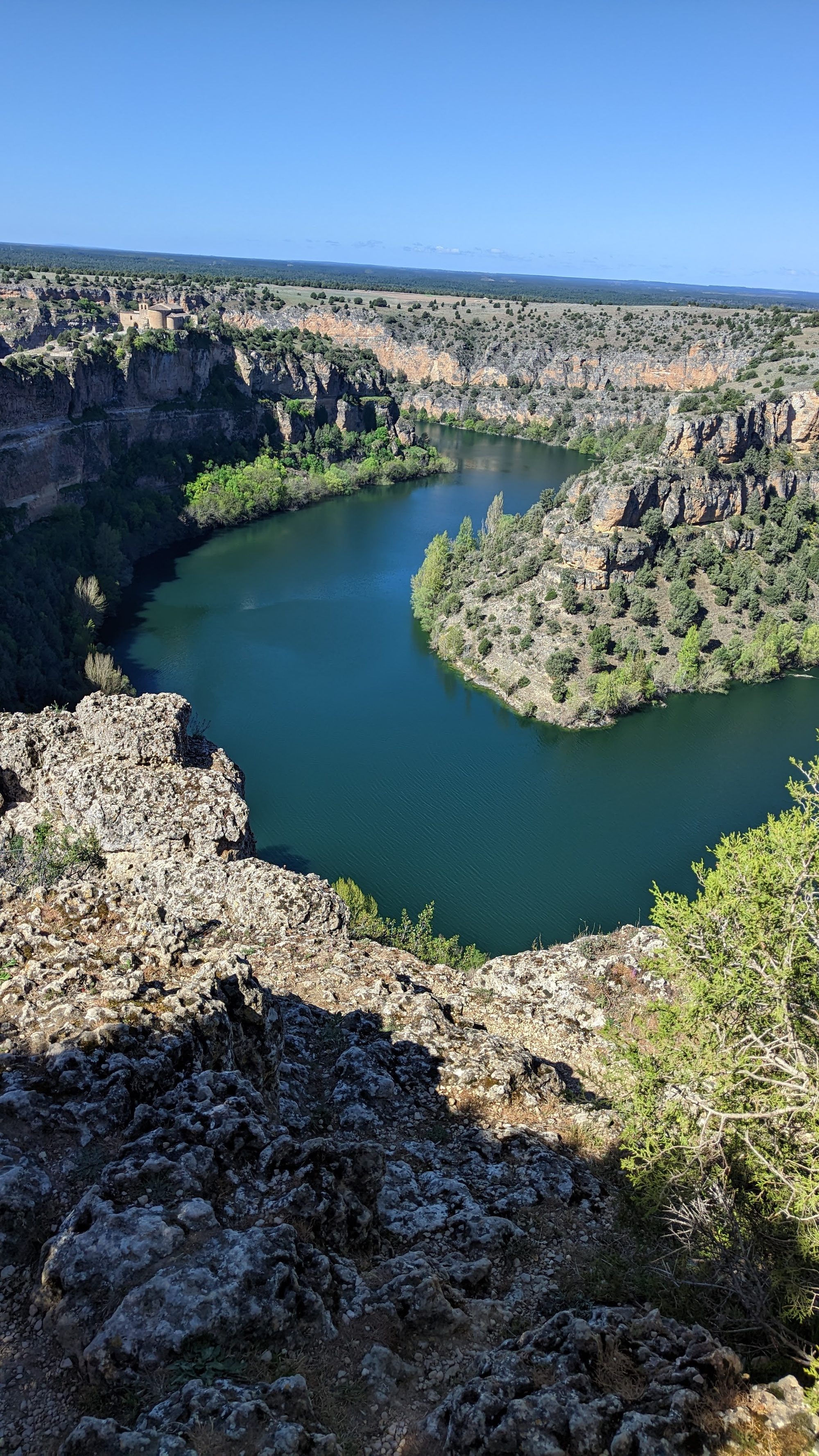 Meandro de un río entre cañones rocosos y acantilados con vegetación.