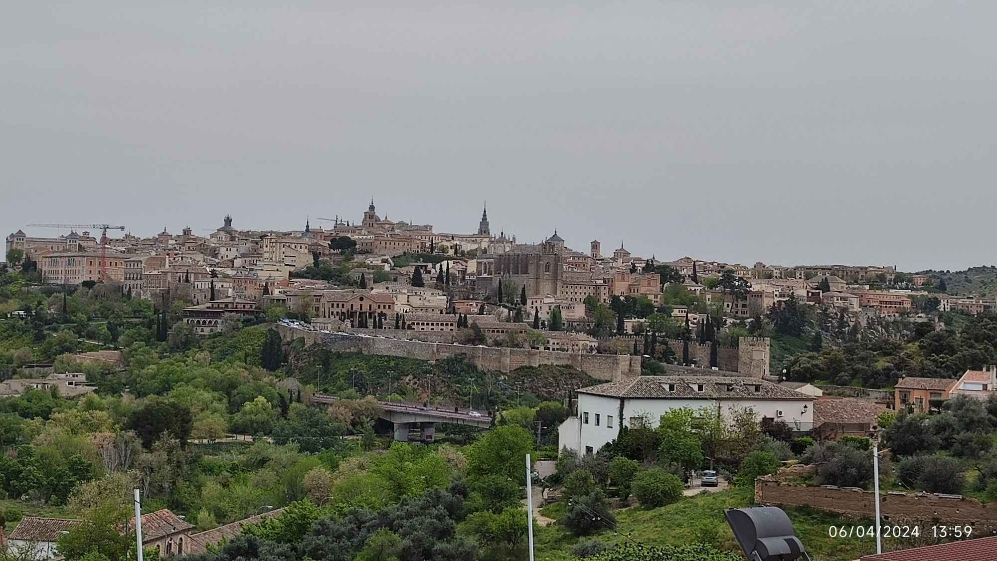 Vista panorámica del casco histórico de Toledo rodeado de murallas y vegetación.