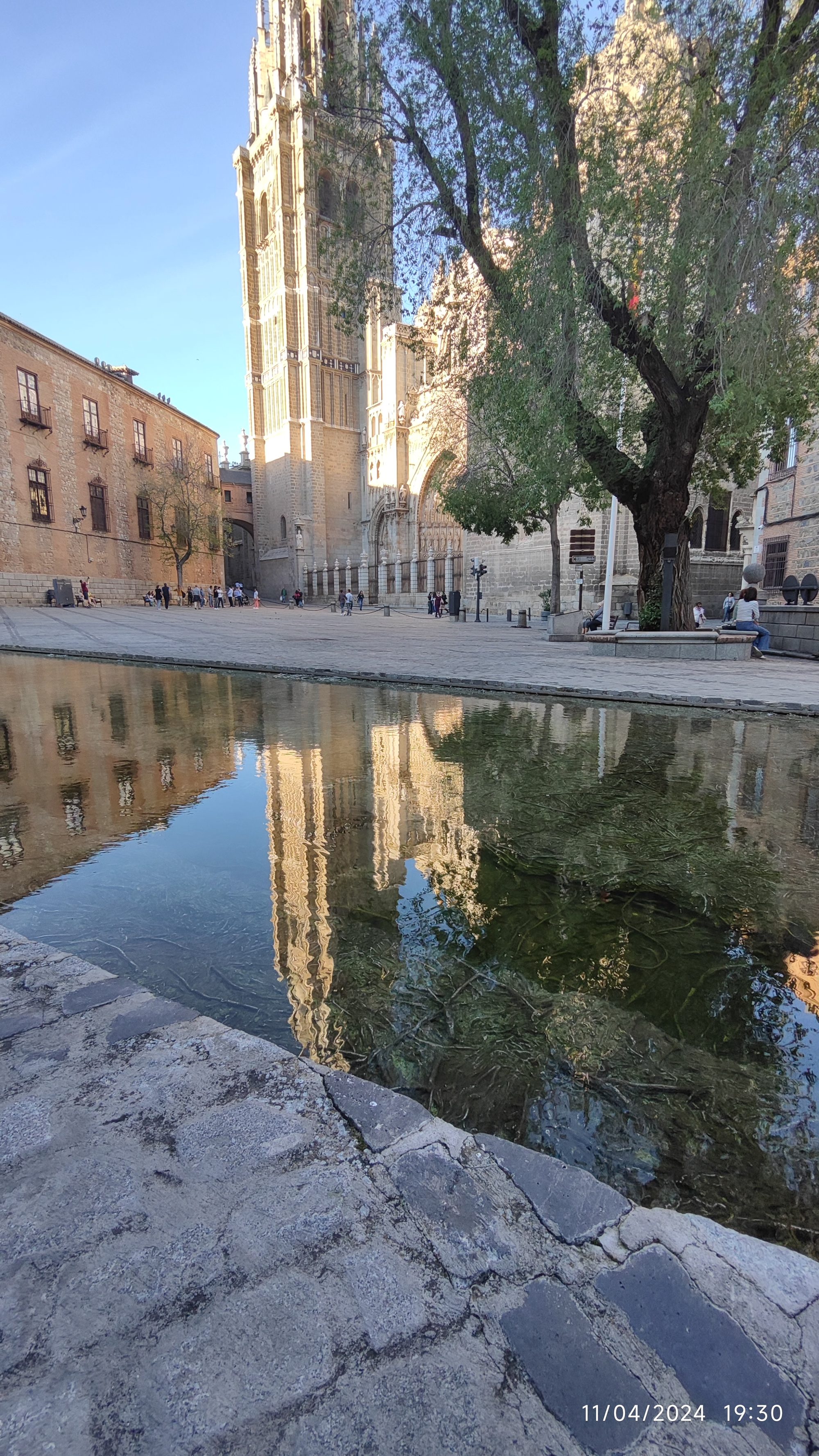 Torre de la Catedral de Toledo y sus edificios históricos reflejados en el agua.