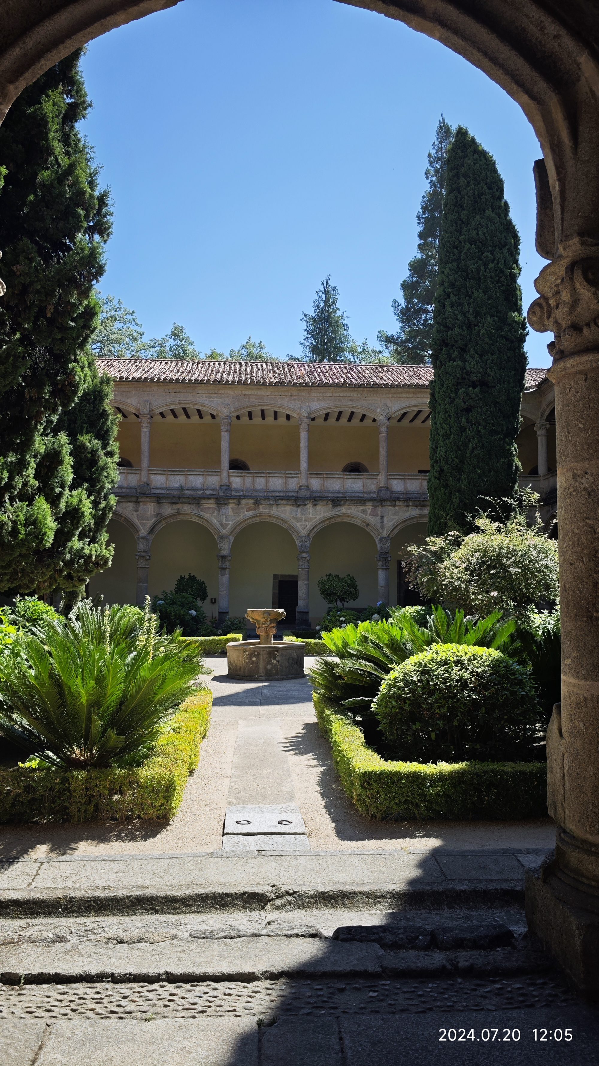 Jardín interior con fuente central y arquería de piedra en un claustro histórico.