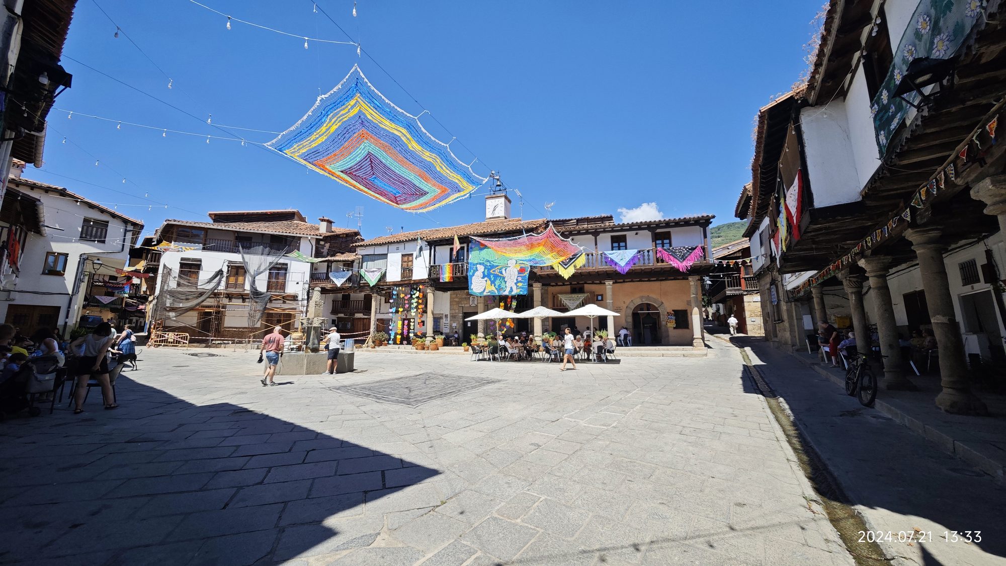 Plaza empedrada en Valverde de la Vera decorada con coloridos parasoles de ganchillo.