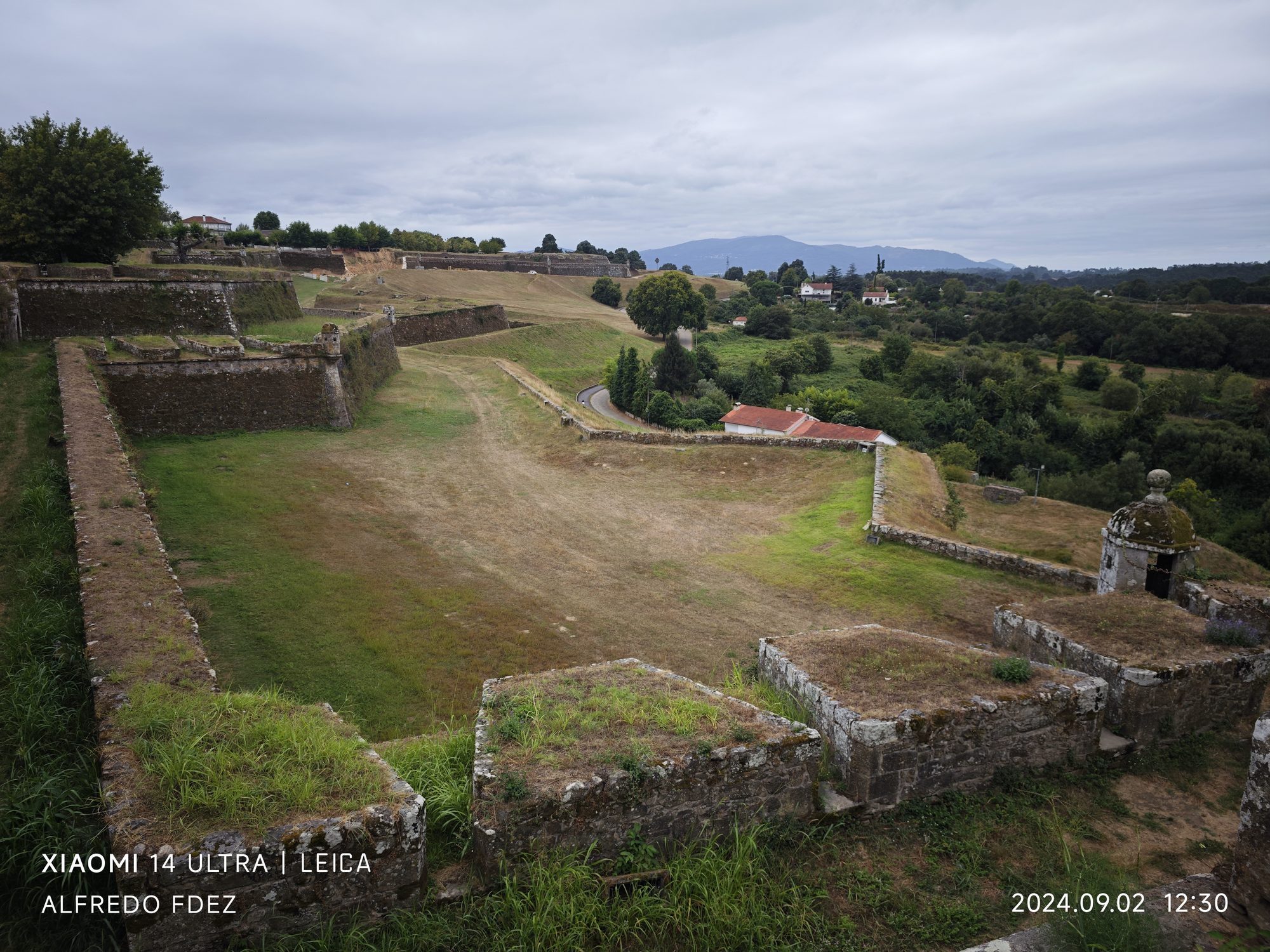 Murallas de piedra y baluartes de la fortaleza histórica de Valença entre campos verdes.