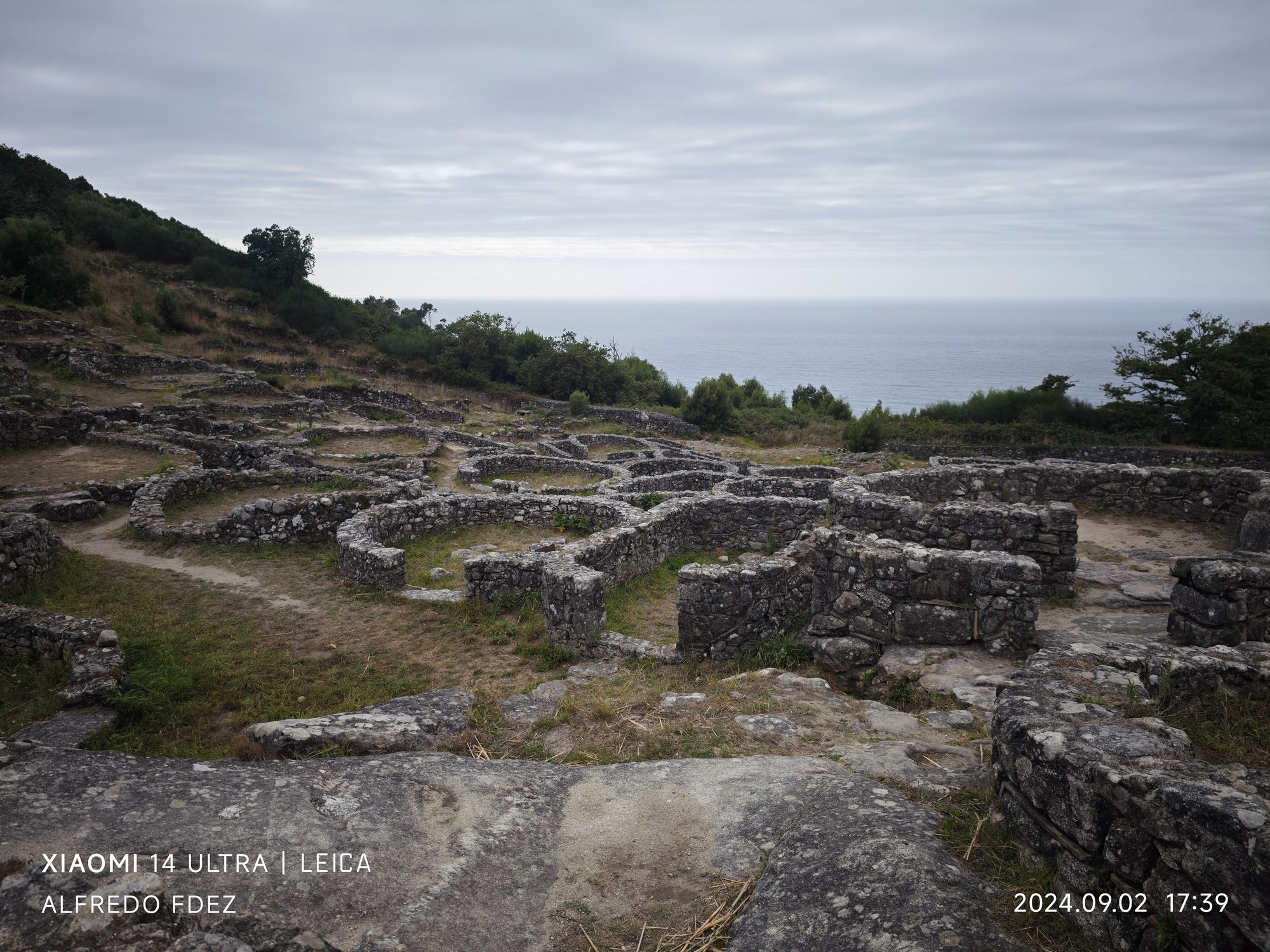 Ruinas de piedra de un castro celta sobre la colina frente al océano Atlántico.
