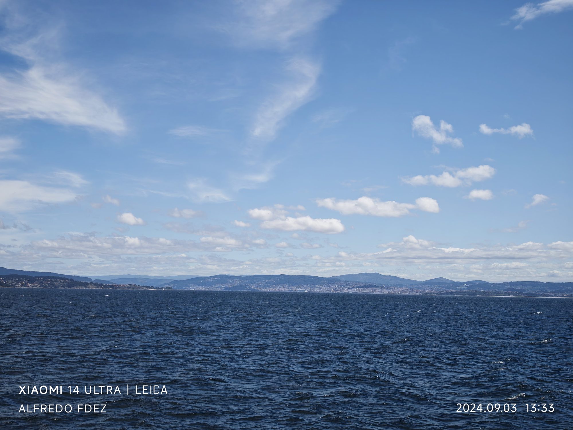 Vista del mar azul y la costa montañosa lejana en Vigo bajo el cielo.