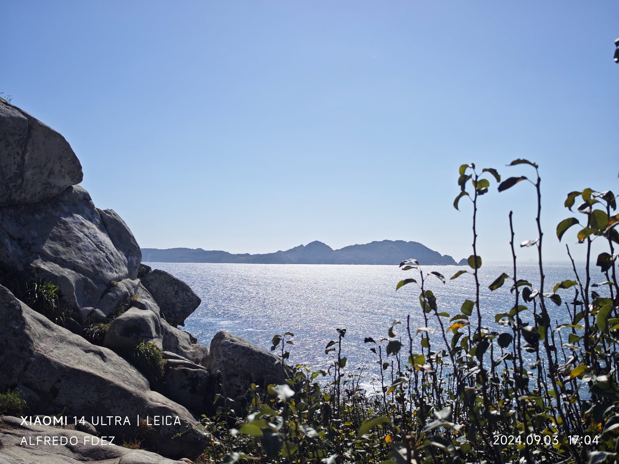 Paisaje costero de mar brillante con rocas de granito e islas en el horizonte.