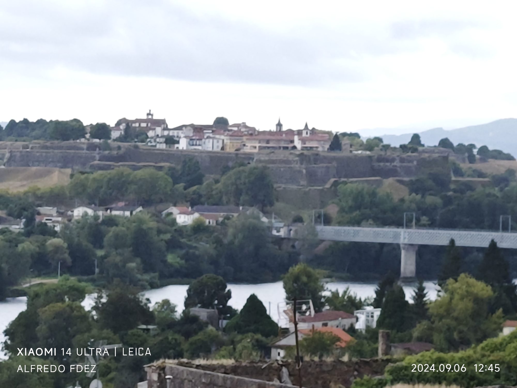 Murallas históricas de la fortaleza de Valença sobre una colina arbolada junto al río.