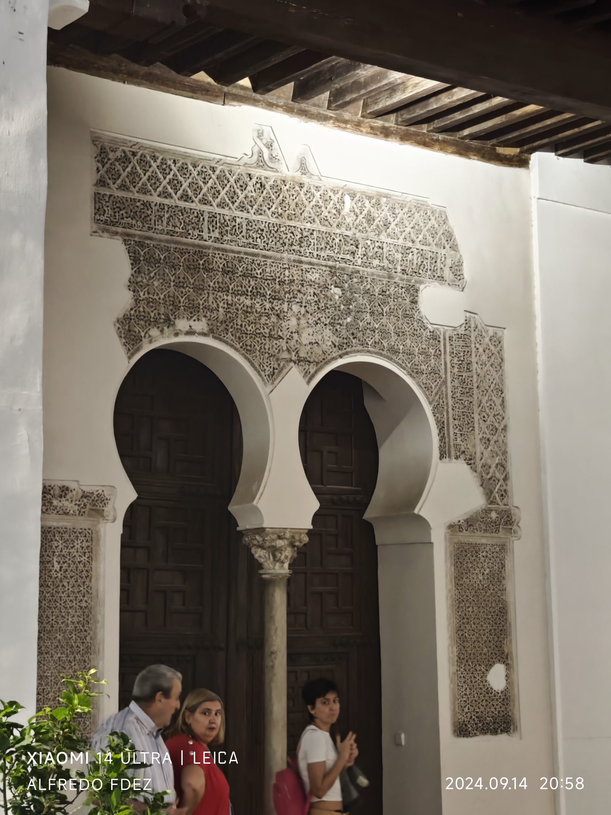 Arcos de herradura de estilo mudéjar con intrincadas yeserías decorativas y puertas de madera.