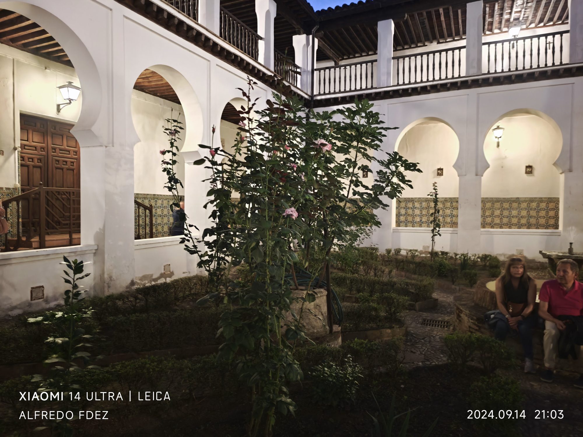 Patio interior de estilo toledano con arcos de herradura, plantas y galerías de madera.