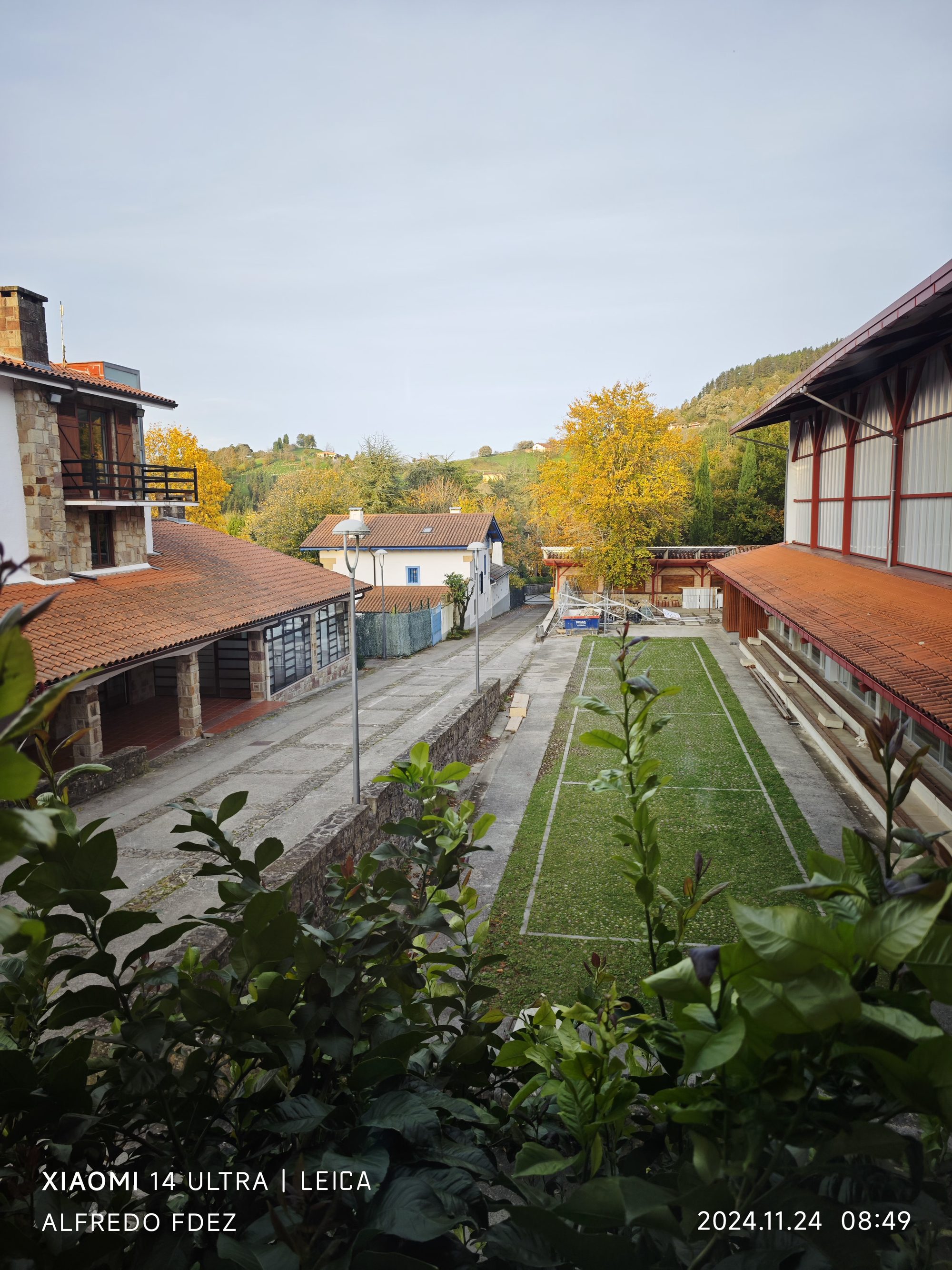 Vista del pueblo de Garai con tejados tradicionales, árboles otoñales y colinas verdes.