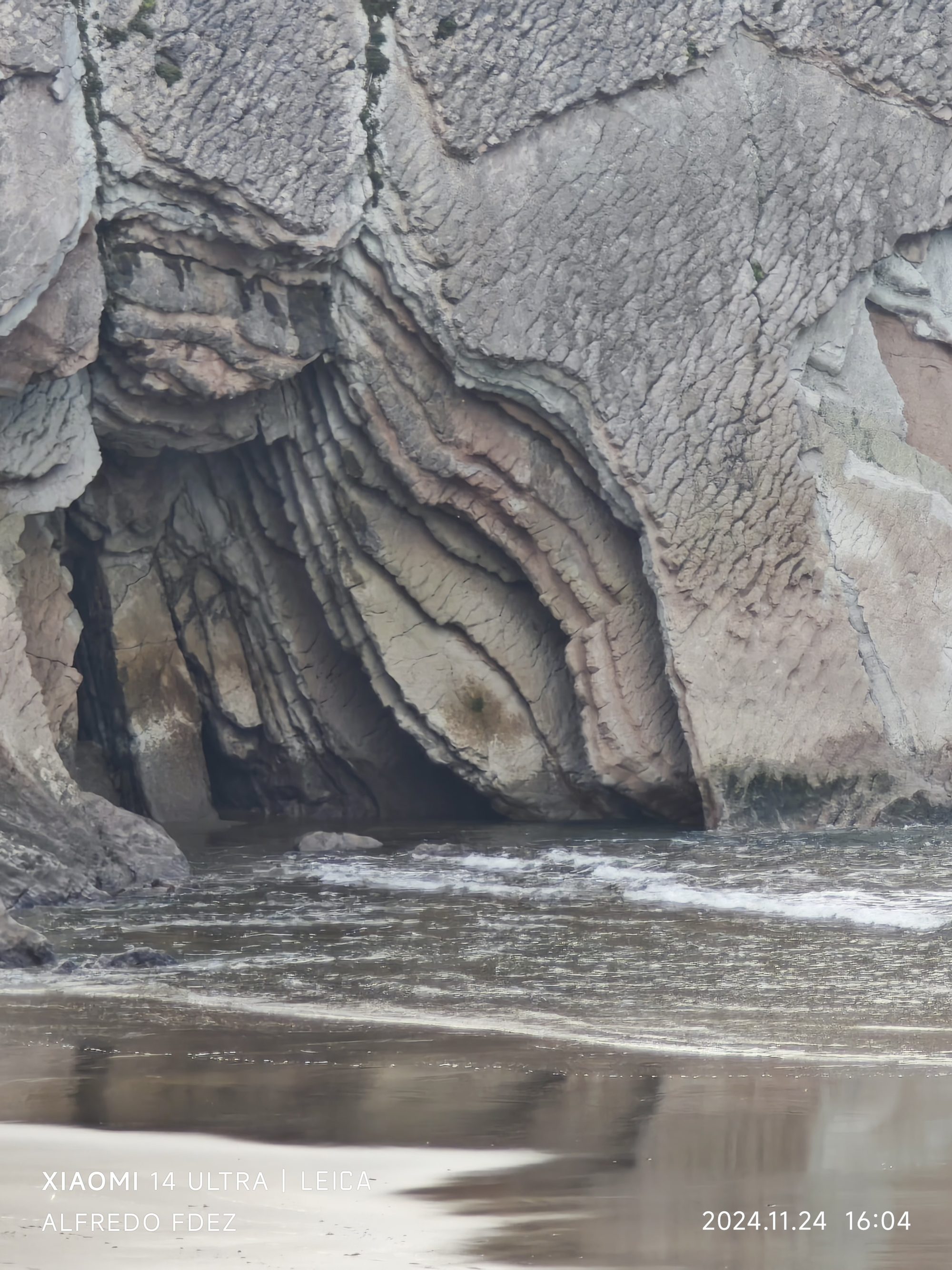 Formaciones rocosas plegadas y estratificadas sobre el agua en la costa de Zumaia.