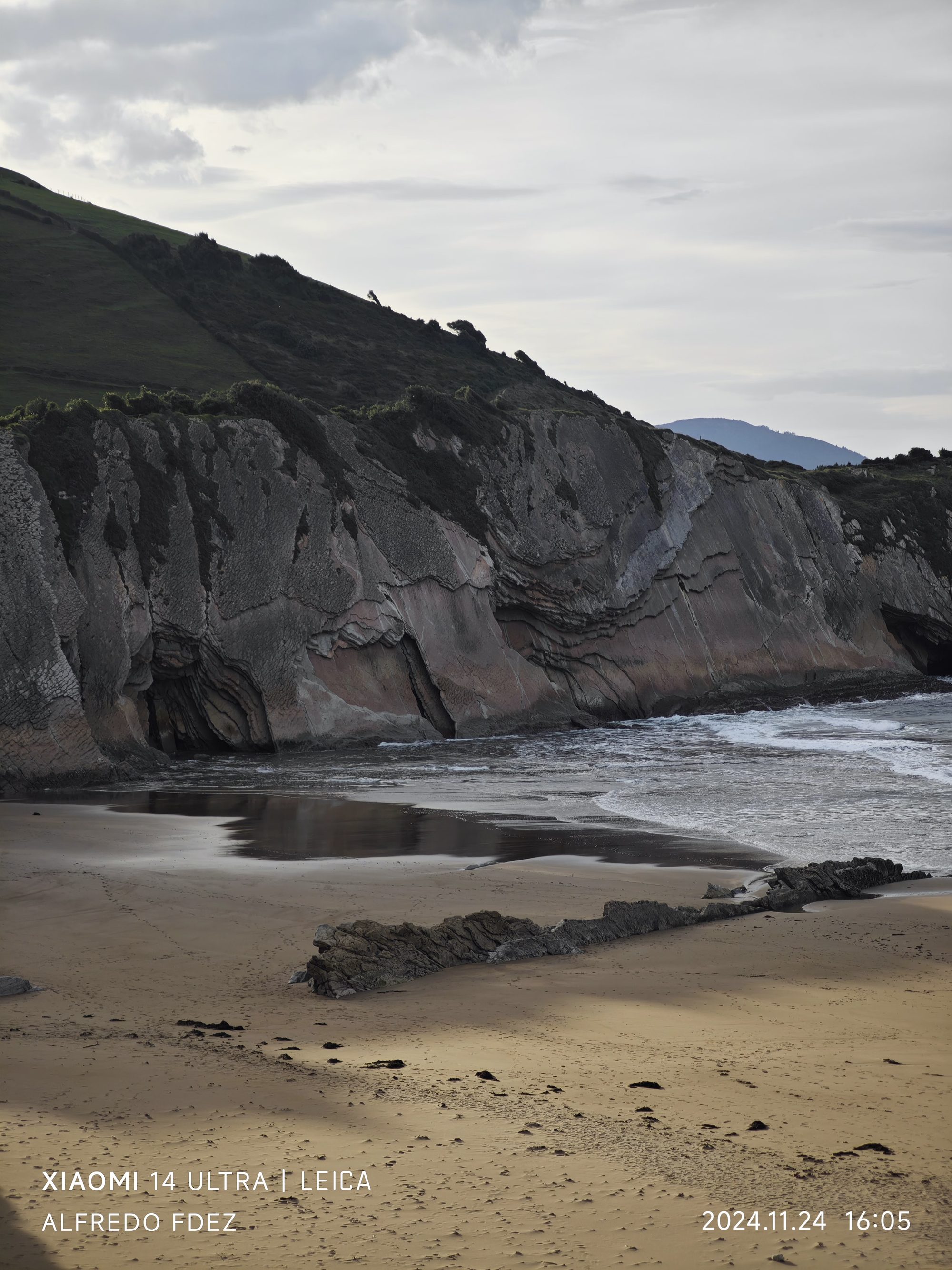 Acantilados rocosos con estratos de flysch en la playa de Zumaia bajo cielo nublado.