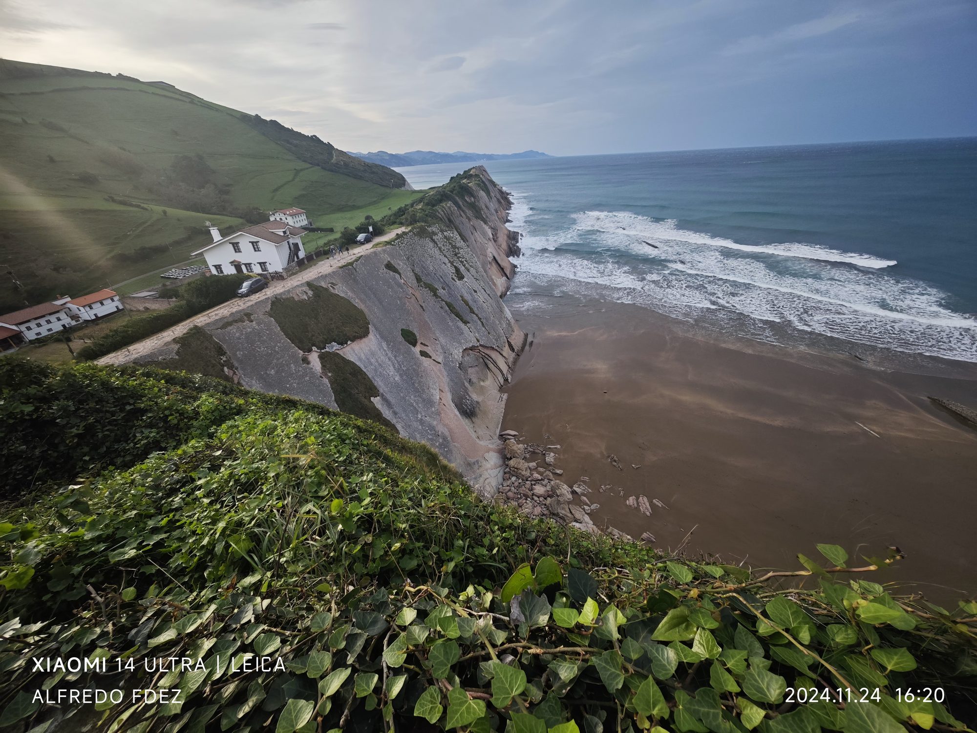 Acantilados sobre la playa de Zumaia con casas blancas en la colina verde.