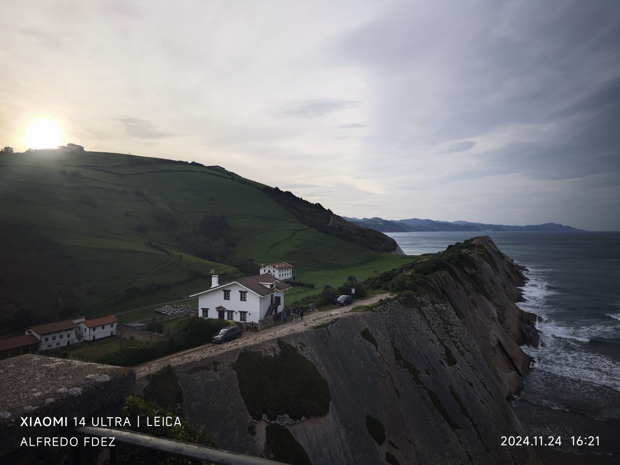 Acantilados verdes y casas blancas junto al mar Cantábrico en Zumaia al atardecer.
