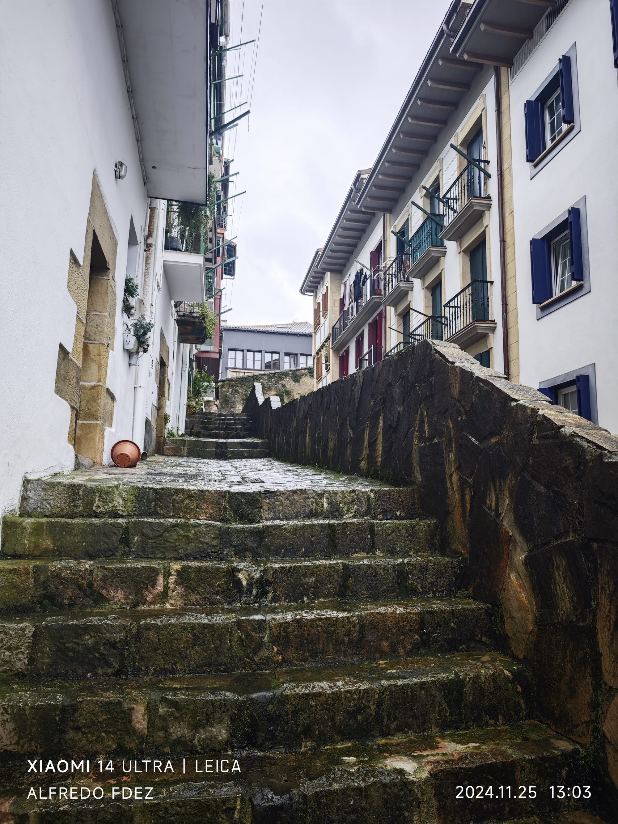 Escalinata de piedra húmeda entre fachadas tradicionales en una calle de Fuenterrabía.