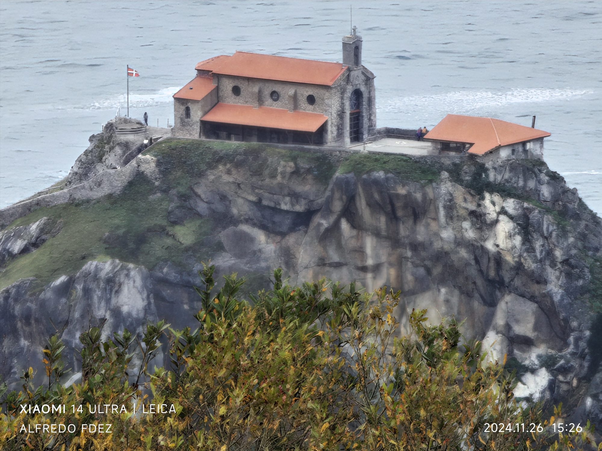 Ermita de San Juan de Gaztelugatxe sobre un acantilado rocoso junto al mar agitado.