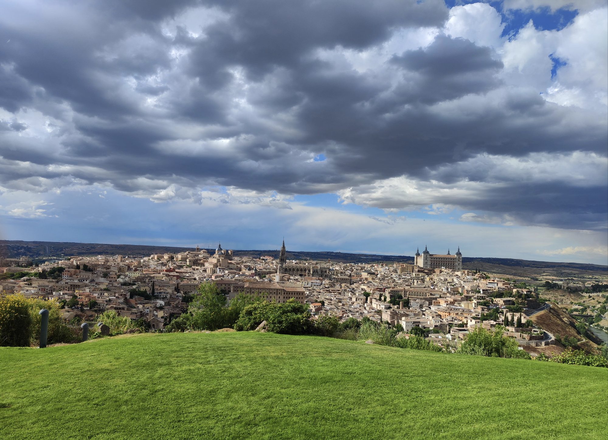 Vista panorámica de Toledo con el Alcázar y la catedral bajo un cielo dramático.