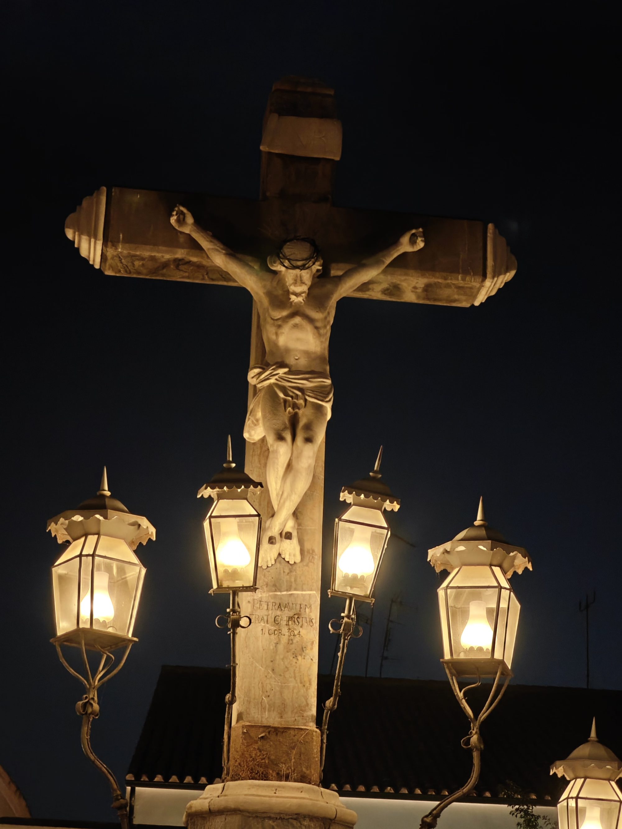 Escultura de Cristo crucificado iluminada por faroles de hierro por la noche en Córdoba.