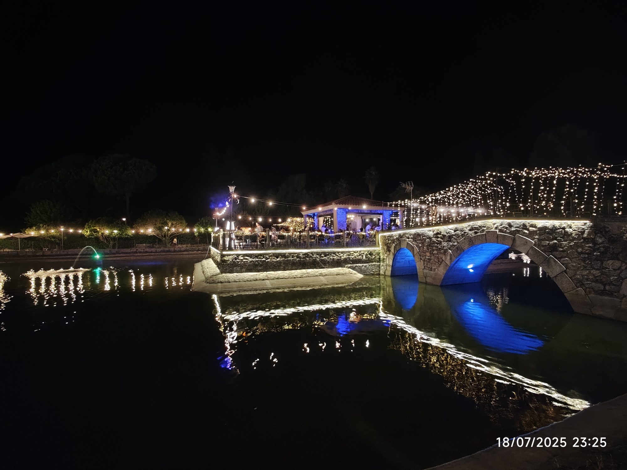 Puente de piedra iluminado de noche sobre el agua en Jarandilla de la Vera.