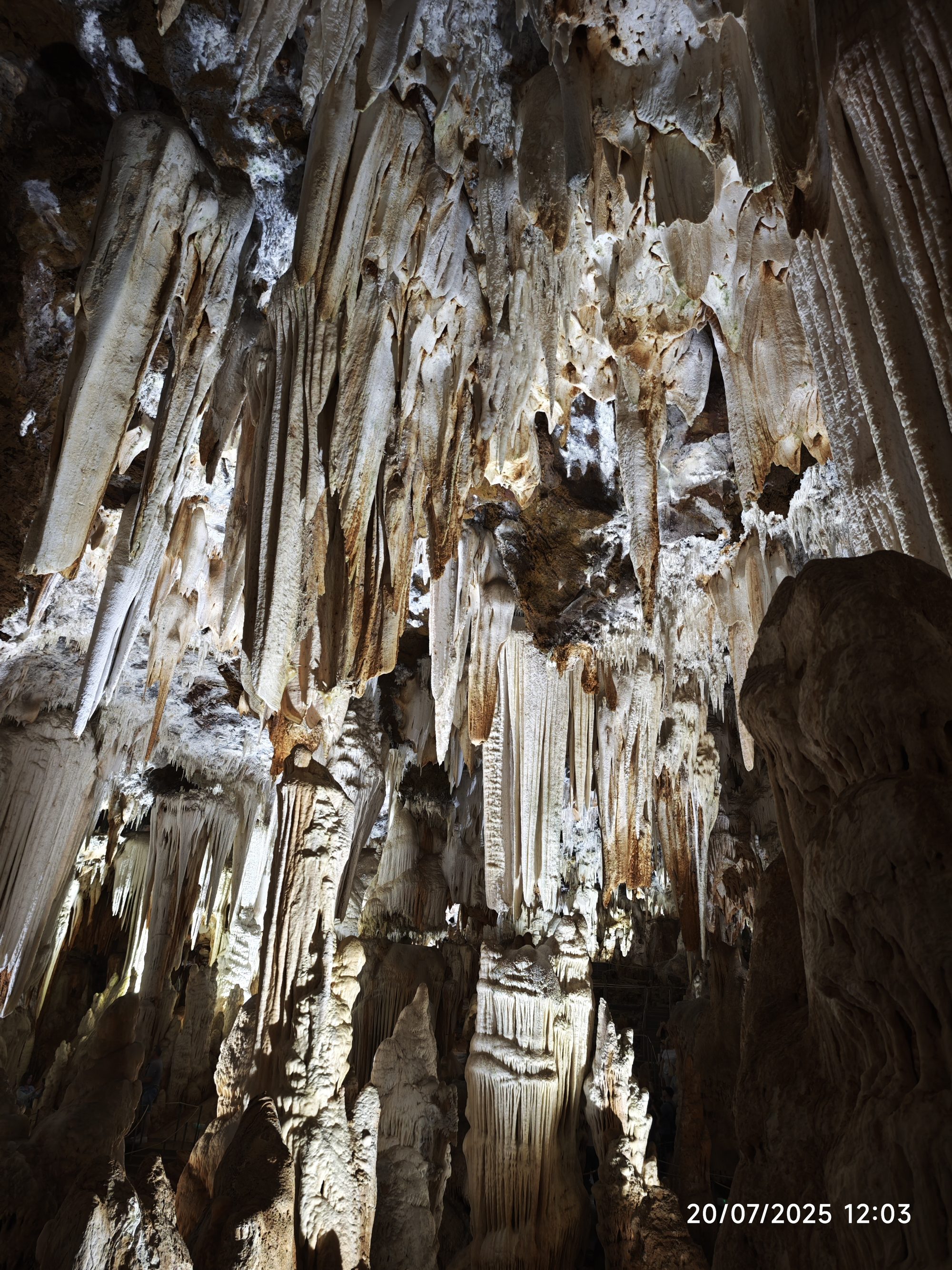 Espectaculares estalactitas y estalagmitas de piedra caliza iluminadas en el interior de una cueva.