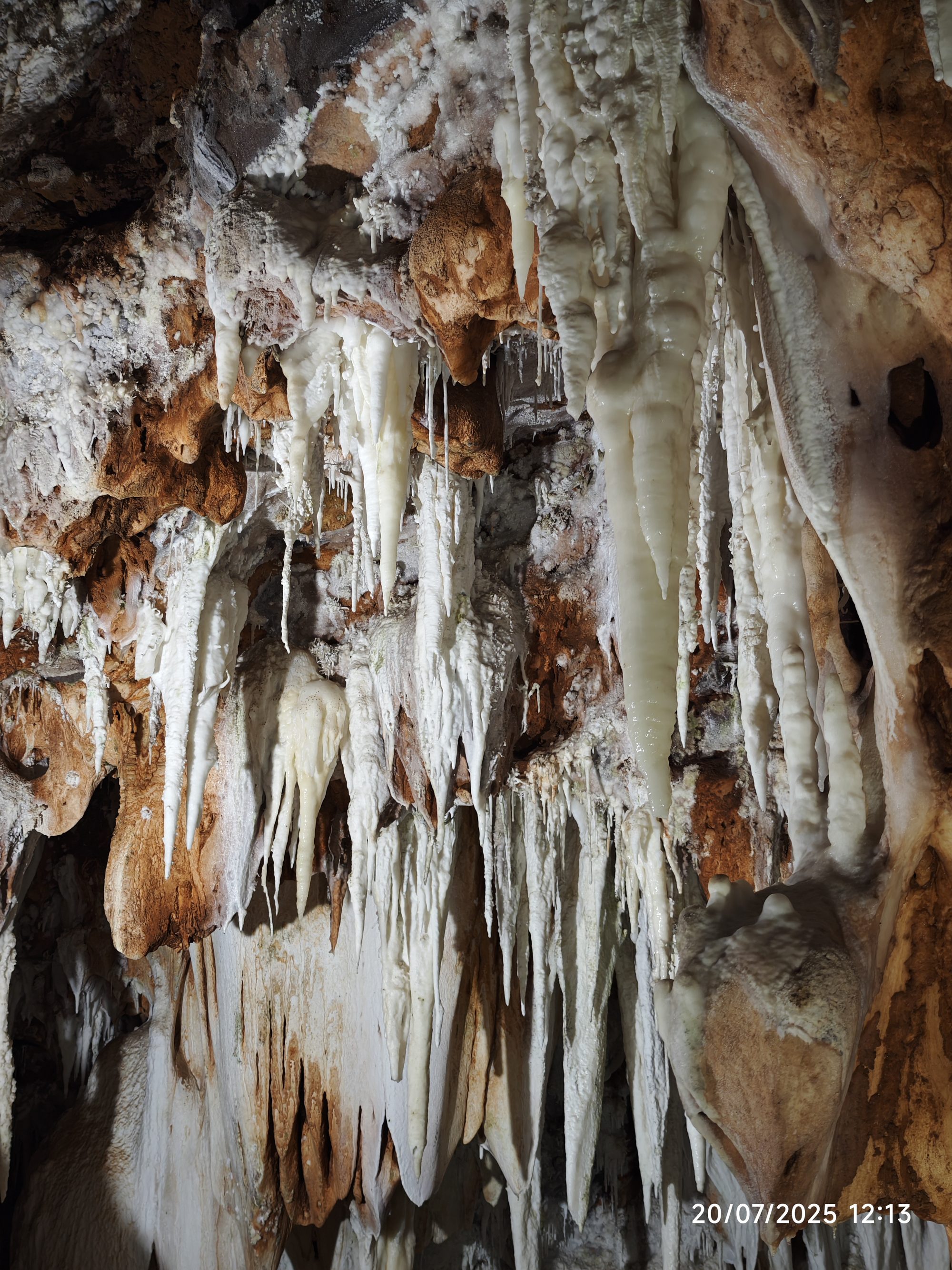 Estalactitas blancas y formaciones rocosas en tonos ocre dentro de una cueva.