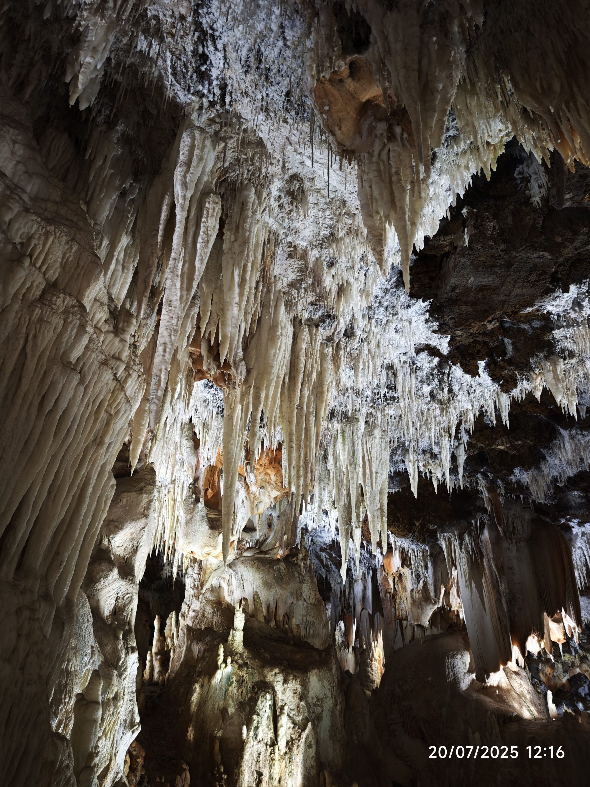 Impresionantes estalactitas y formaciones rocosas iluminadas en el techo de una cueva subterránea.