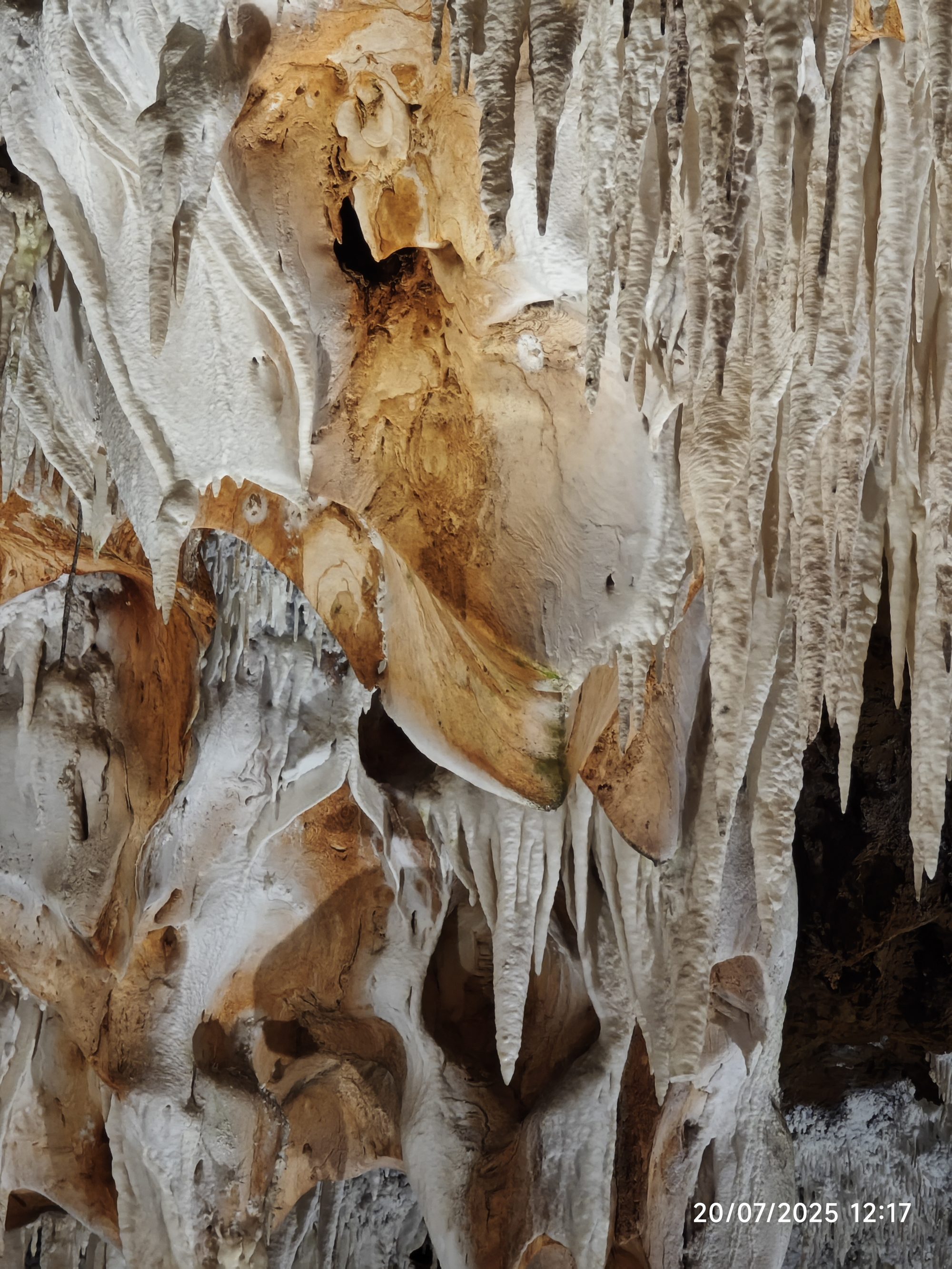 Formaciones de estalactitas calcáreas en tonos ocres y blancos dentro de una cueva subterránea.
