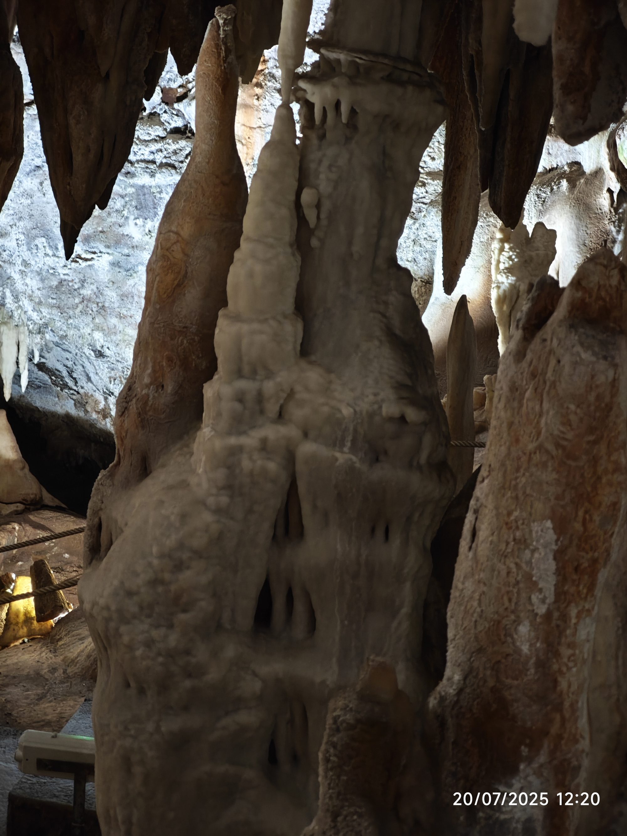 Grandes columnas de estalagmitas y estalactitas iluminadas en el interior de una cueva.