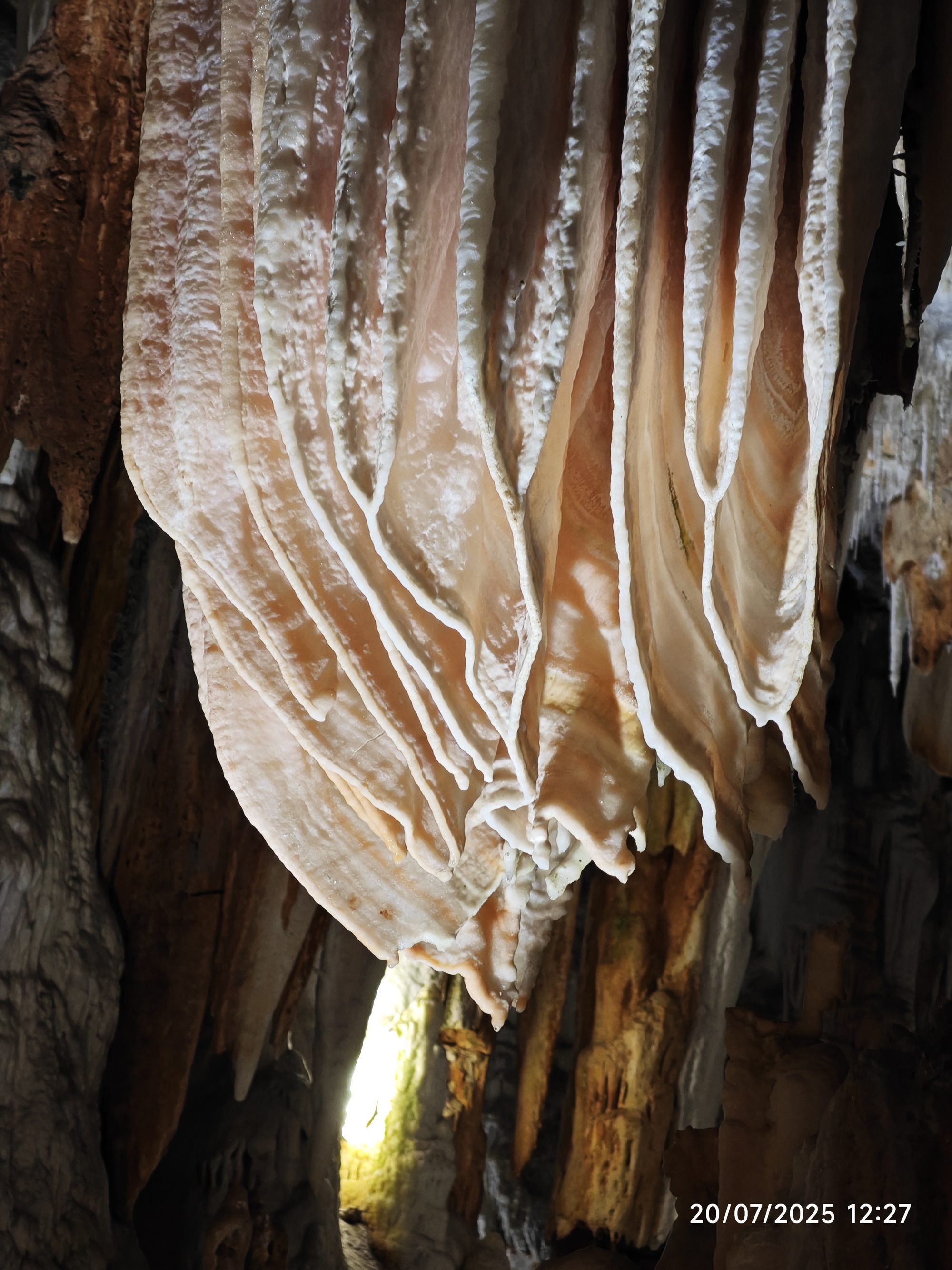 Formaciones calcáreas en forma de cortinas onduladas en el interior de una cueva.