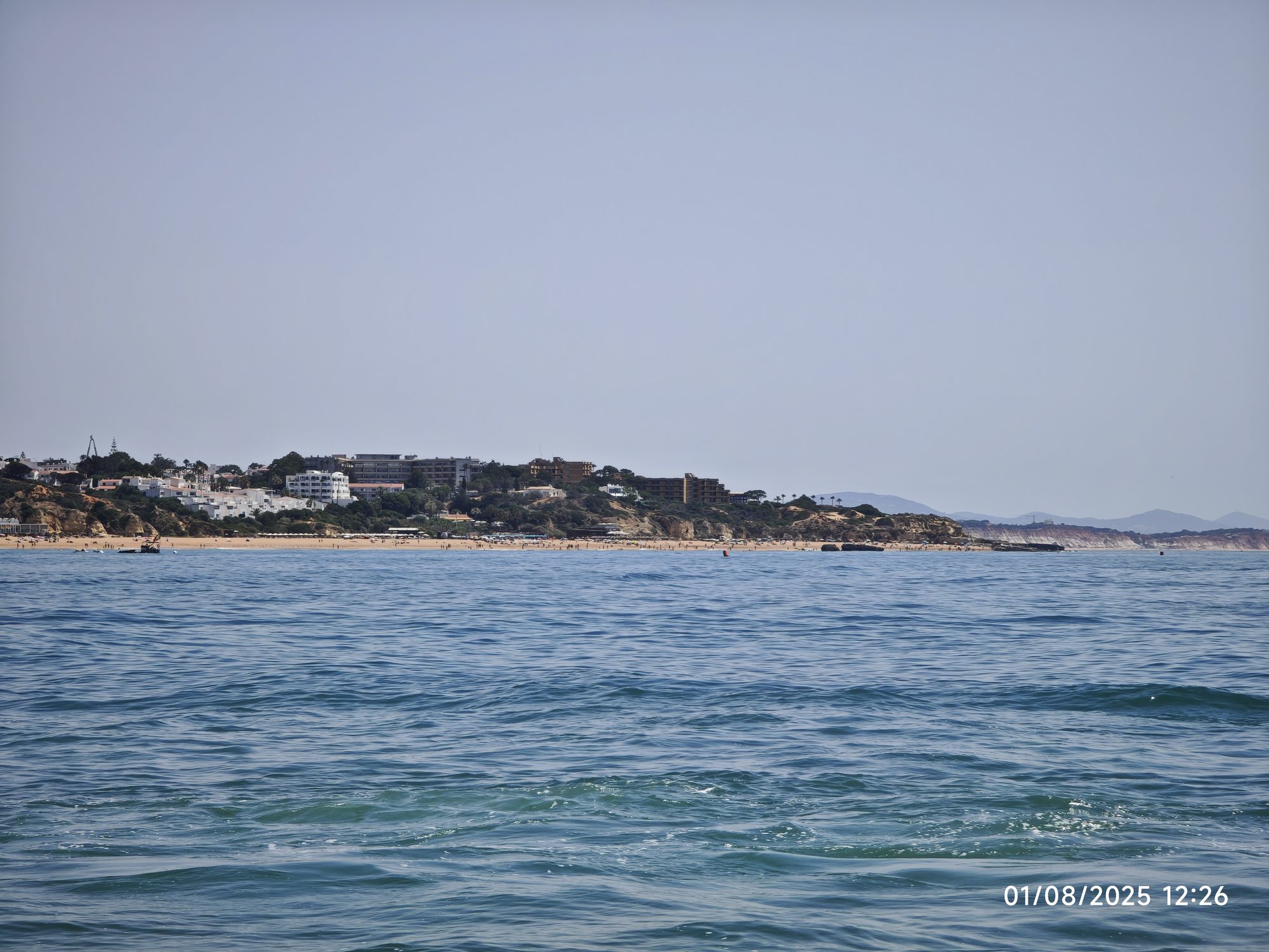 Costa de Albufeira con playas y edificios vista desde las aguas azules del mar.