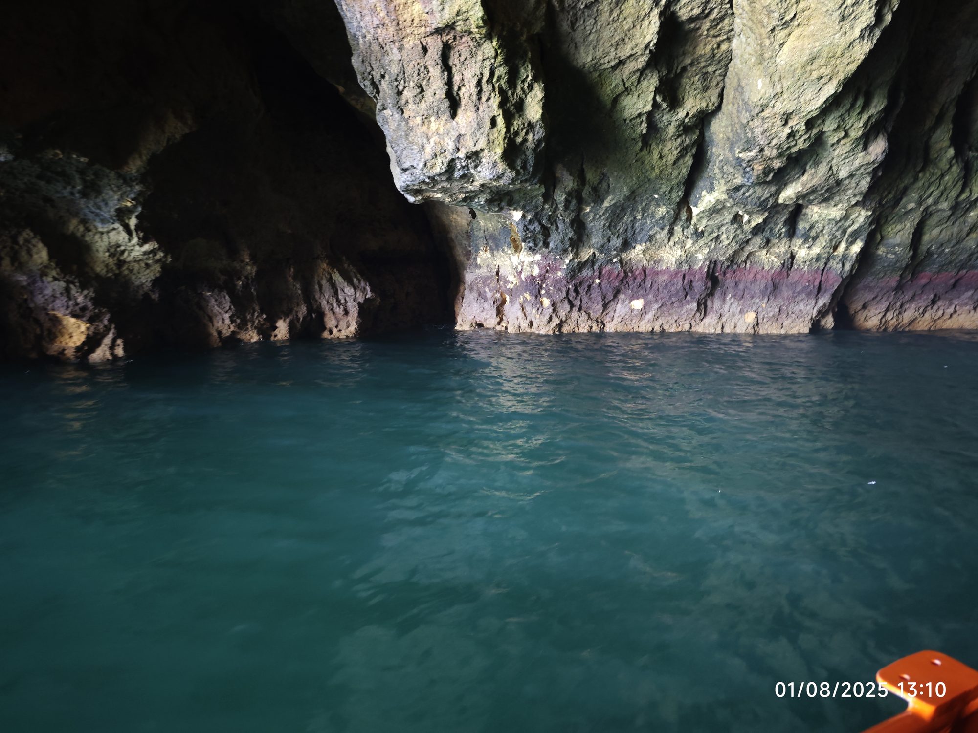 Interior de una cueva marina con paredes rocosas y agua cristalina de color turquesa