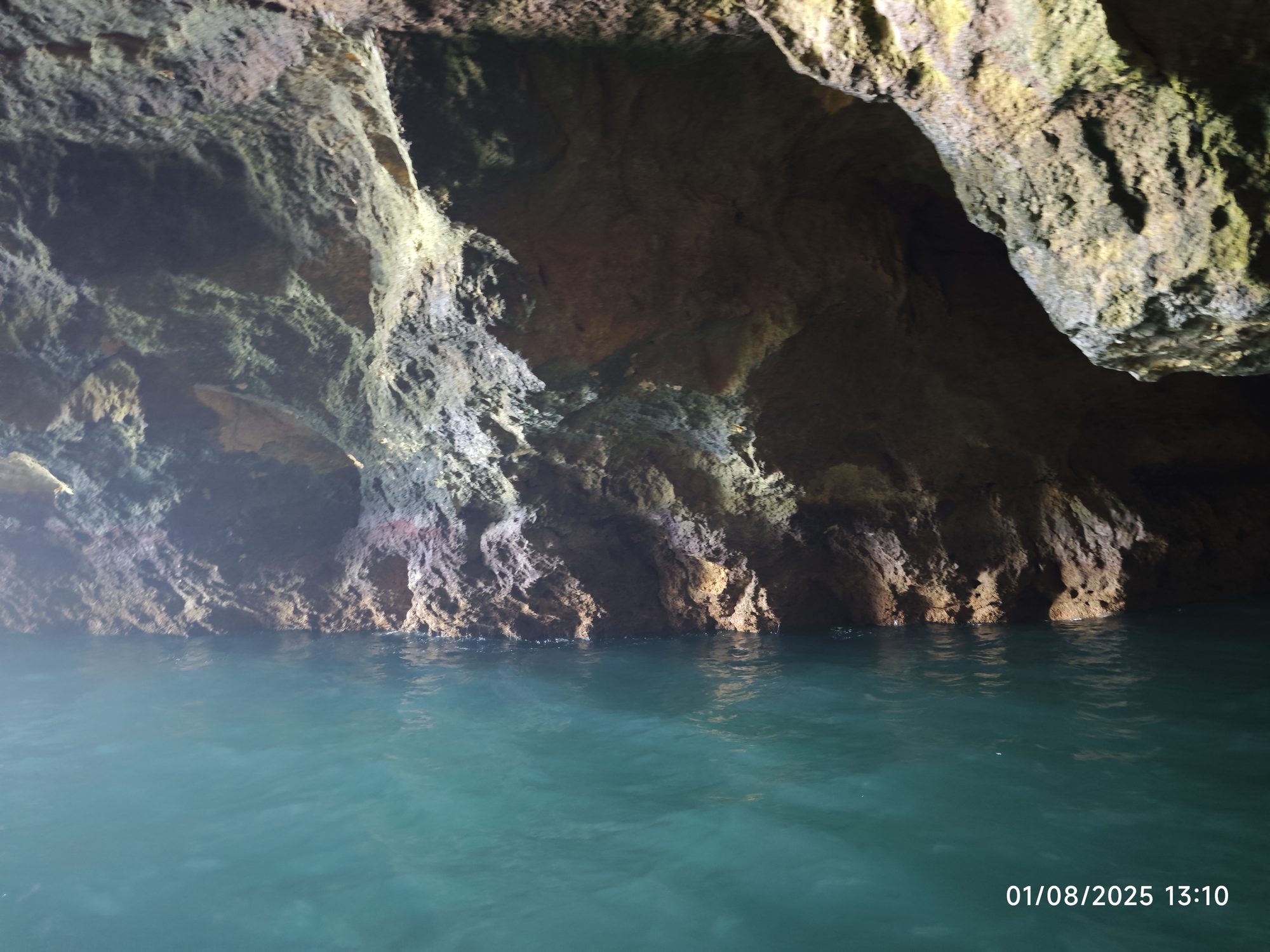 Interior de una cueva marina con formaciones rocosas y aguas turquesas cristalinas.