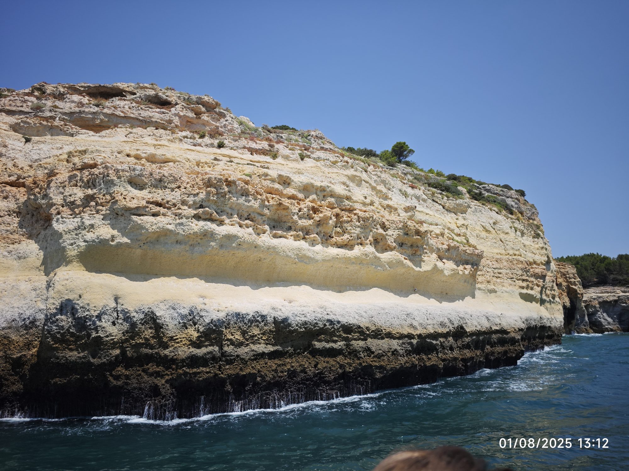 Acantilados de piedra caliza dorada erosionados junto al mar turquesa de Portugal.