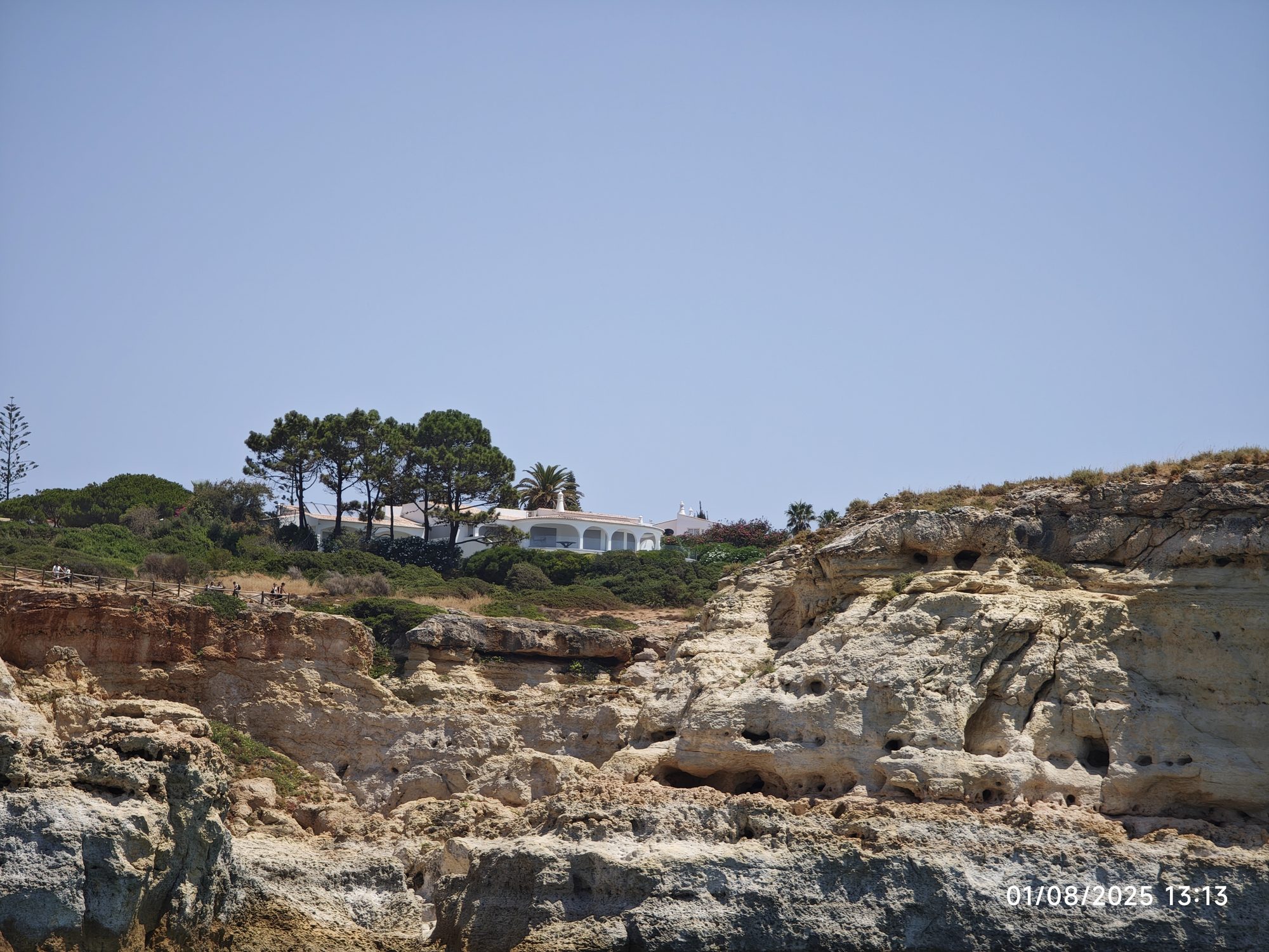 Acantilados de roca caliza con una casa blanca y pinos en Lagoa e Carvoeiro.