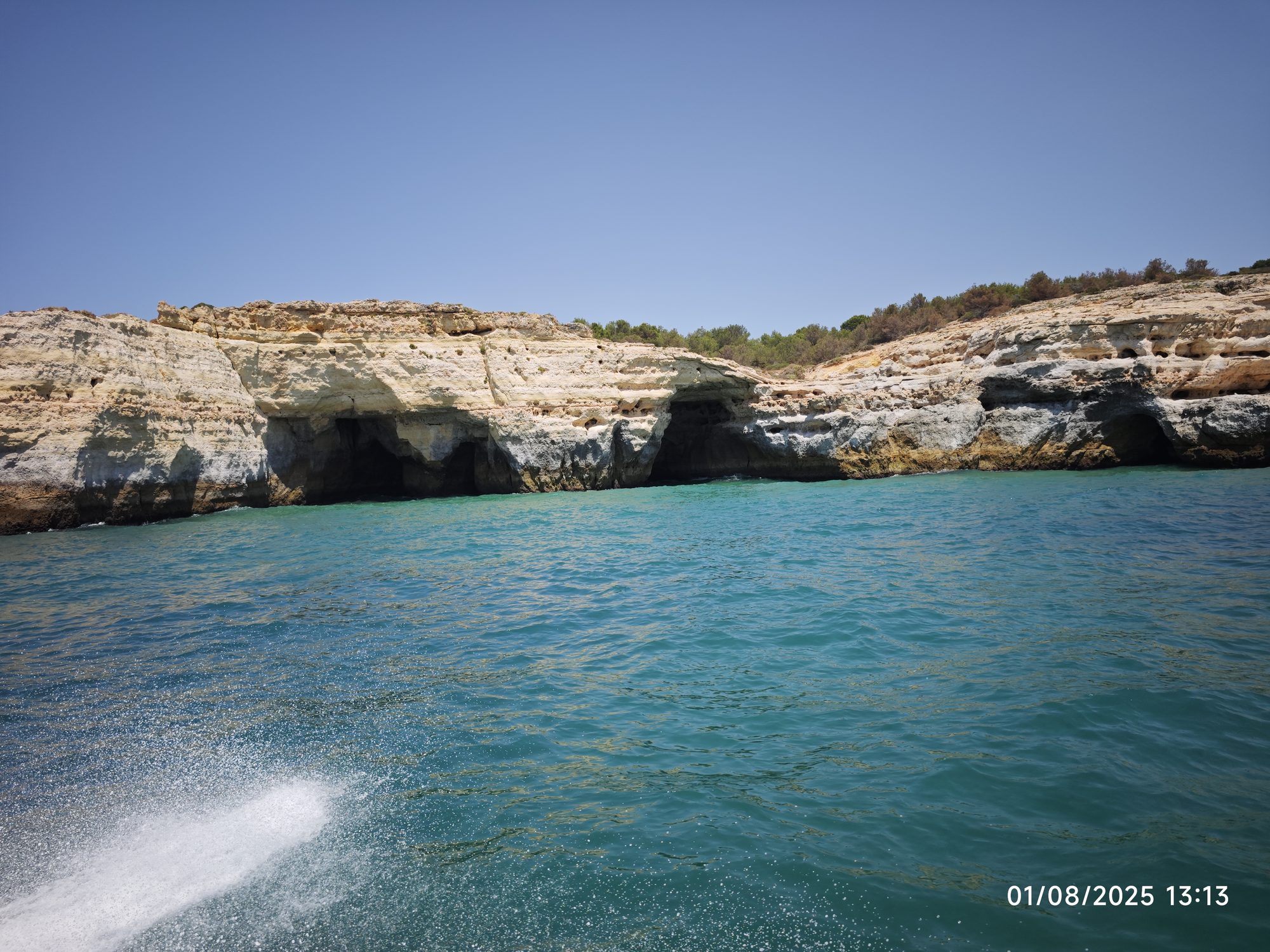Acantilados dorados y cuevas marinas rodeados por aguas turquesas en la costa portuguesa.
