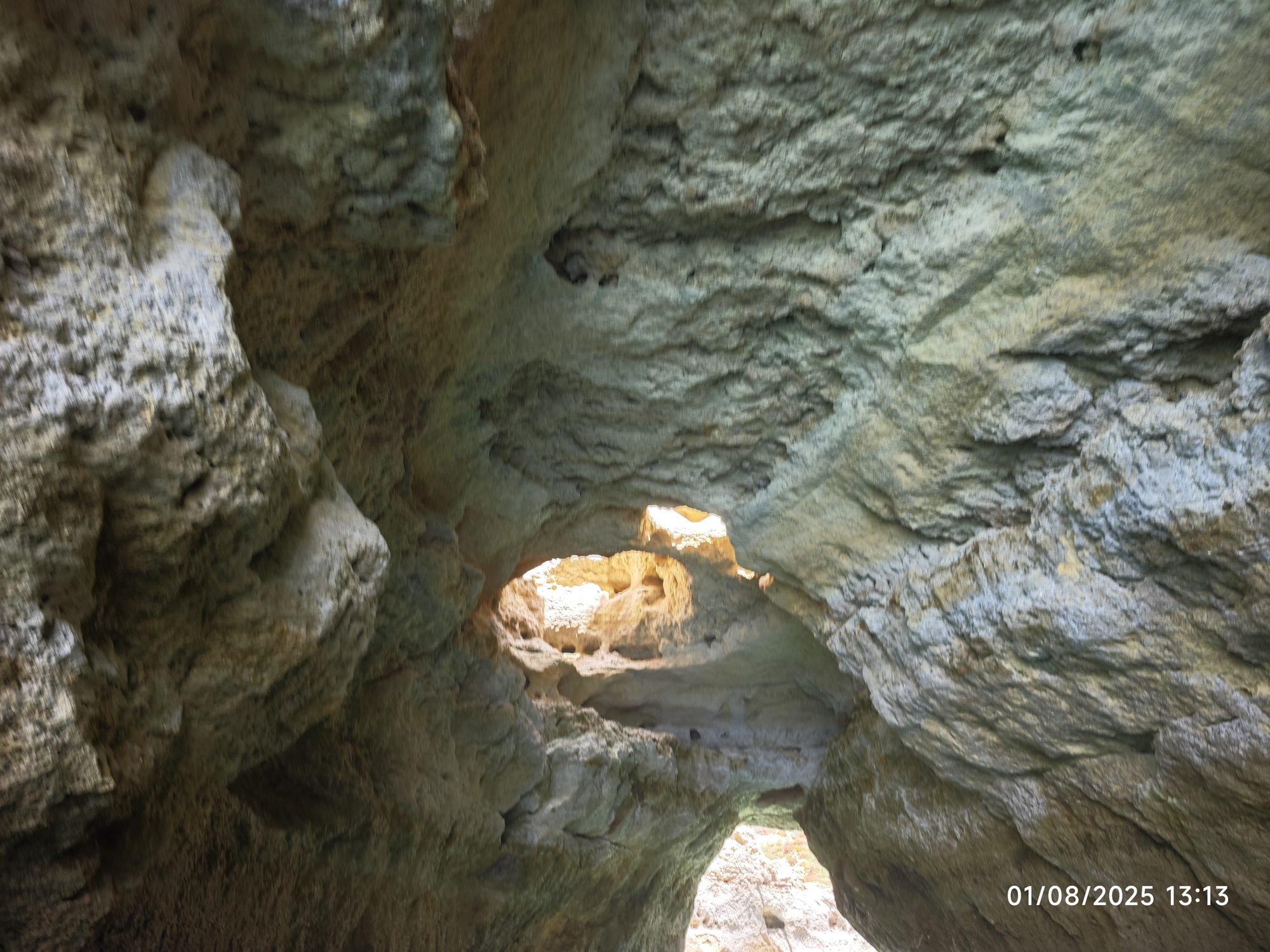 Interior de una cueva marina de roca caliza con luz natural entrando por el techo.
