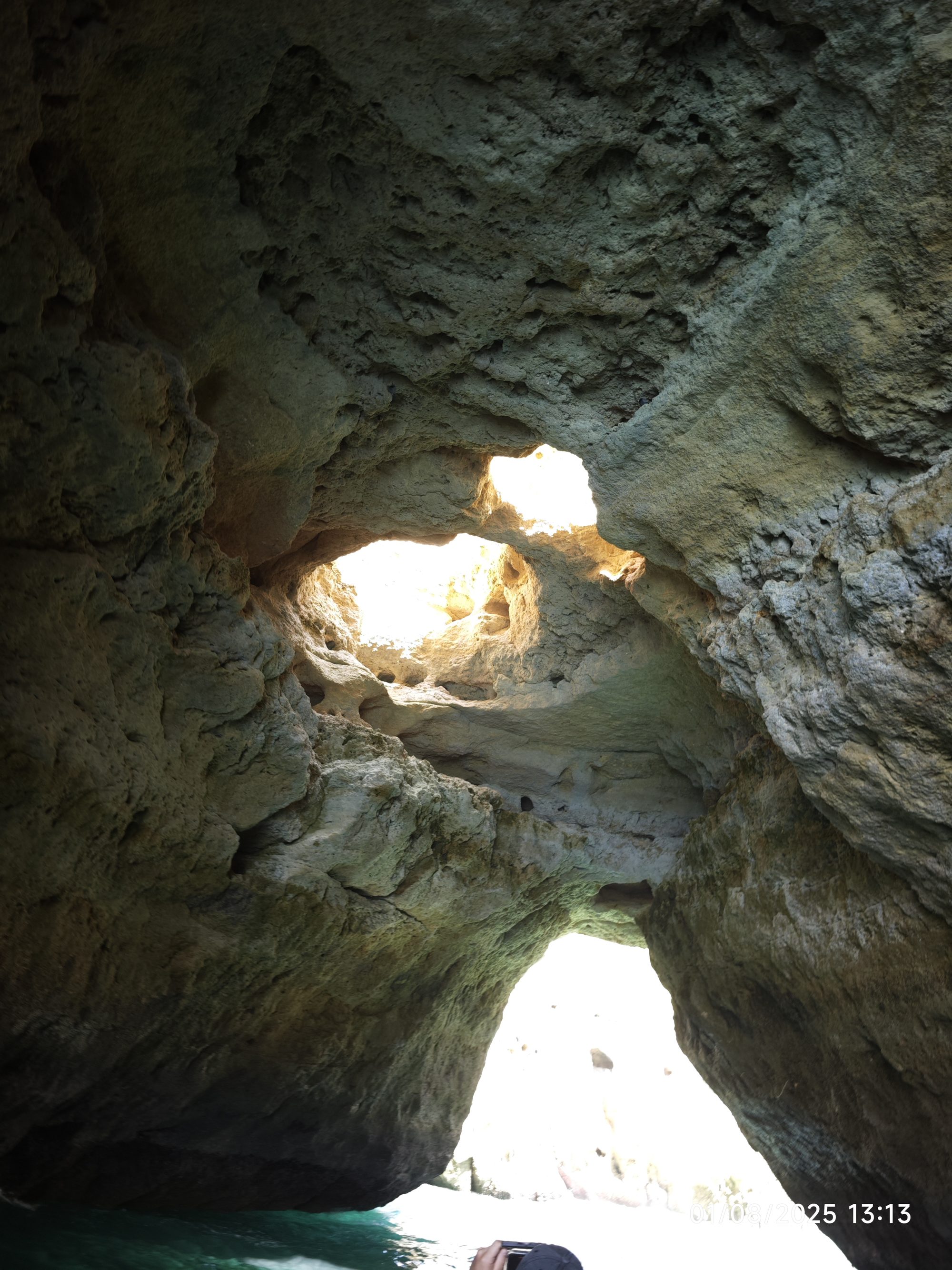 Interior de una cueva marina con aberturas rocosas por donde entra la luz solar.