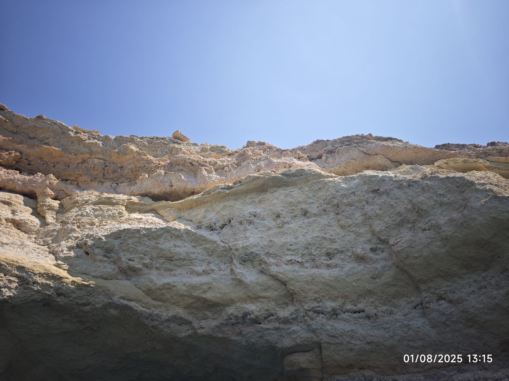 Acantilados de piedra caliza dorada bajo un cielo azul totalmente despejado en la costa.
