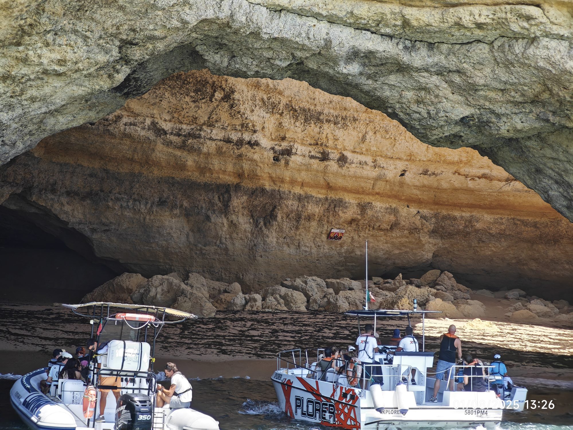 Embarcaciones turísticas entrando en una majestuosa cueva marina de acantilados dorados.