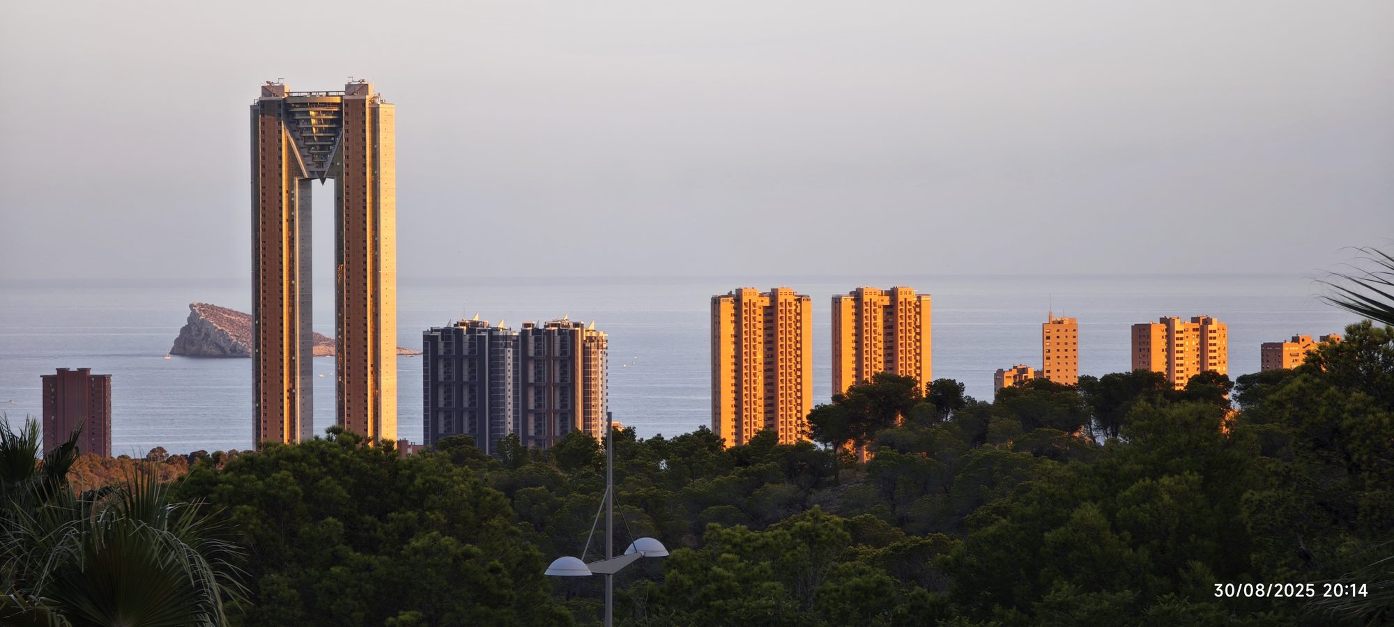 Rascacielos de Benidorm y la isla al fondo iluminados por la luz dorada del atardecer.