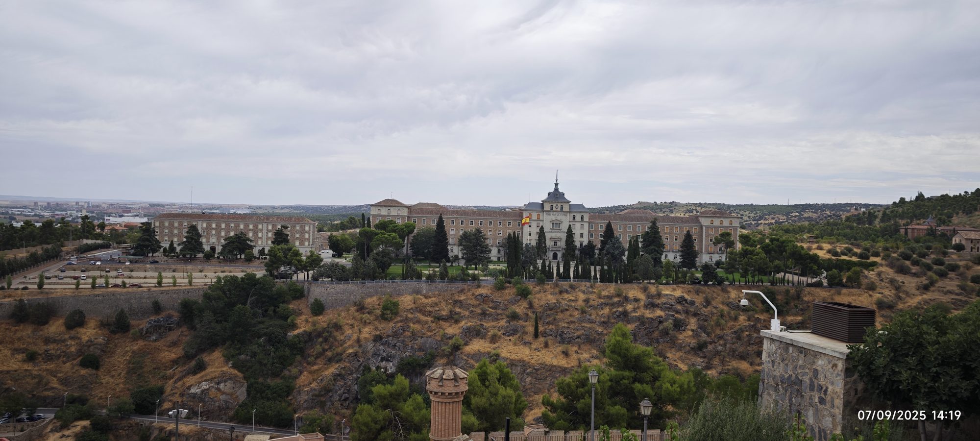 Vista panorámica de la Academia de Infantería de Toledo sobre colinas y cielo nublado.