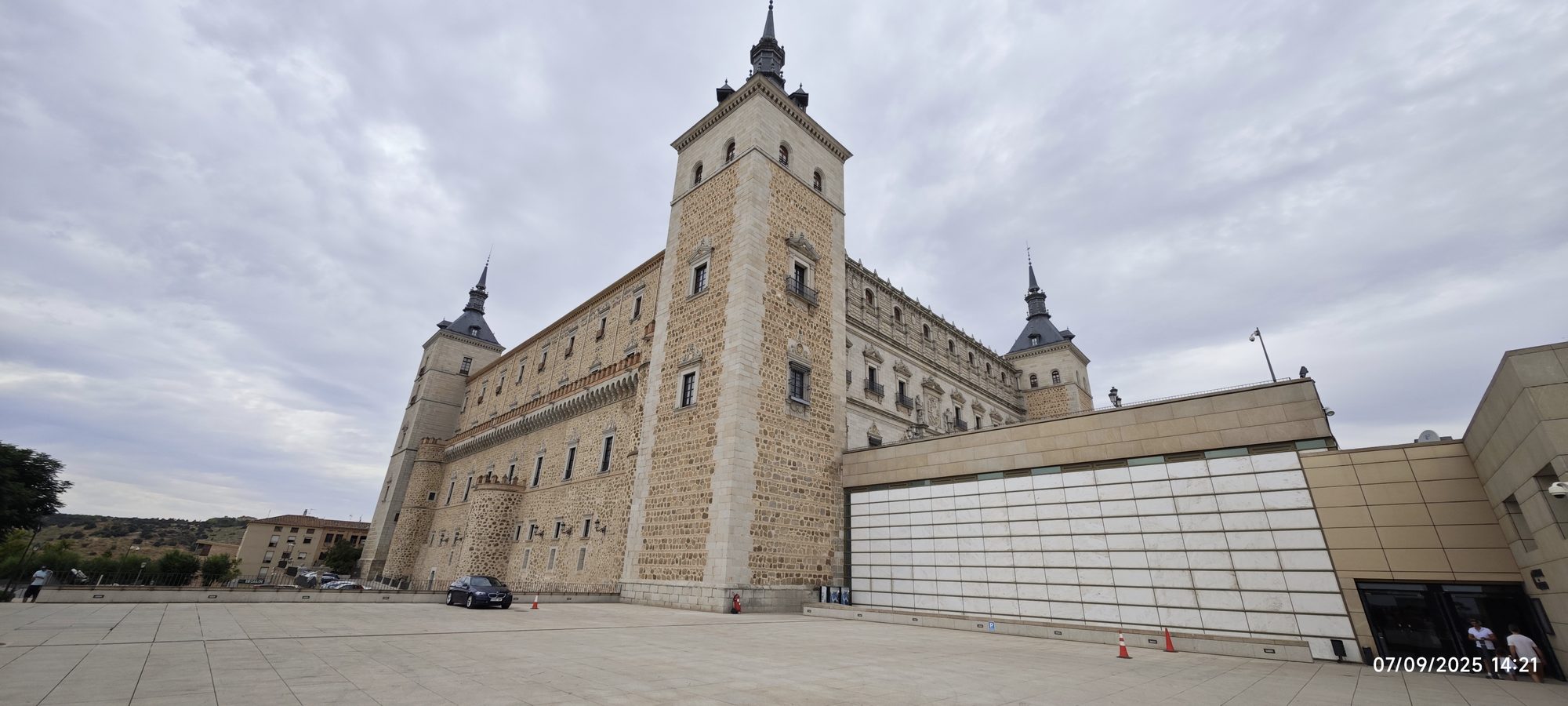 Imponente Alcázar de Toledo con sus torres de chapitel bajo un cielo nublado.