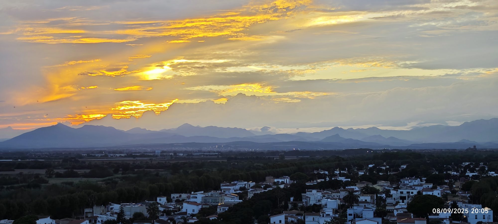 Atardecer dorado sobre las montañas con un pueblo de casas blancas en el valle.