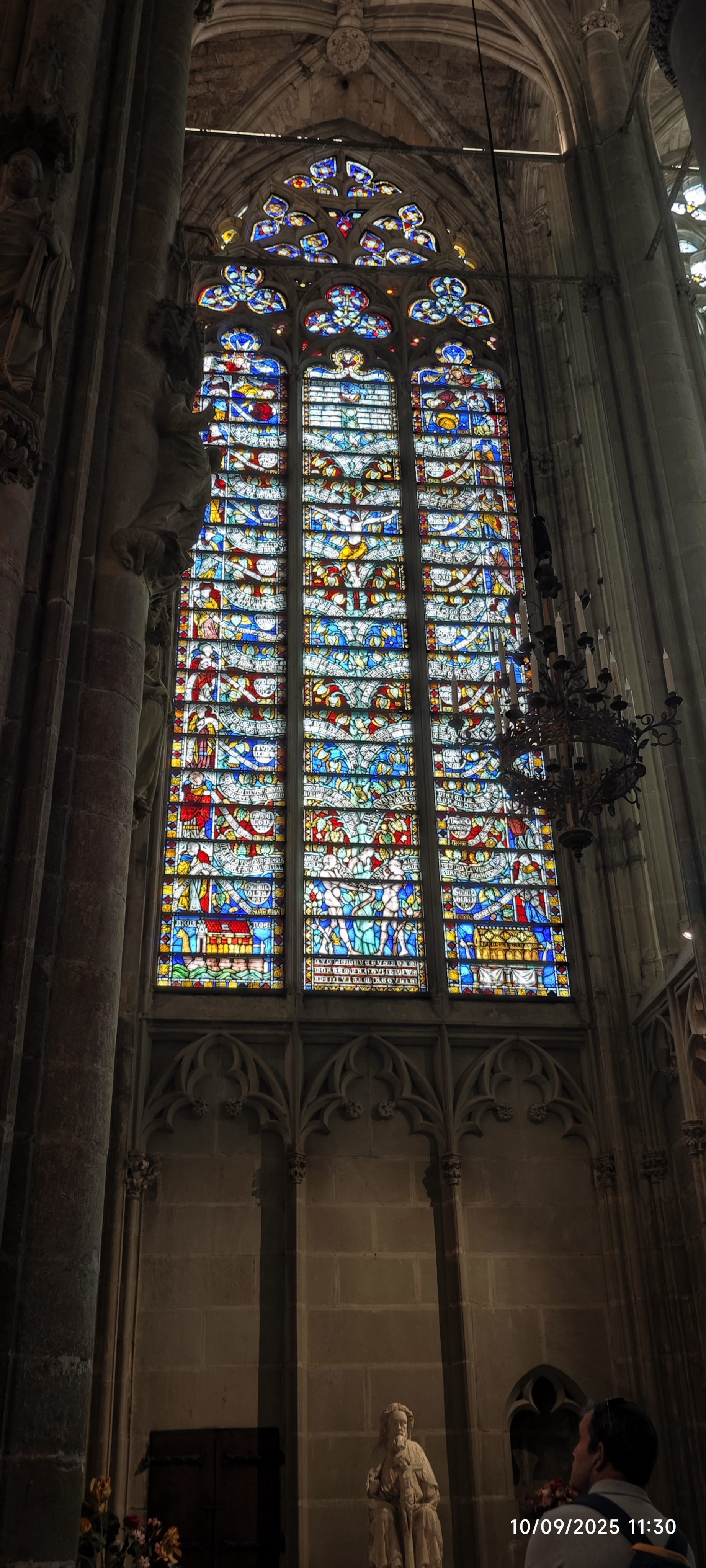 Impresionante vitral gótico con coloridos detalles religiosos en el interior de una iglesia de piedra.