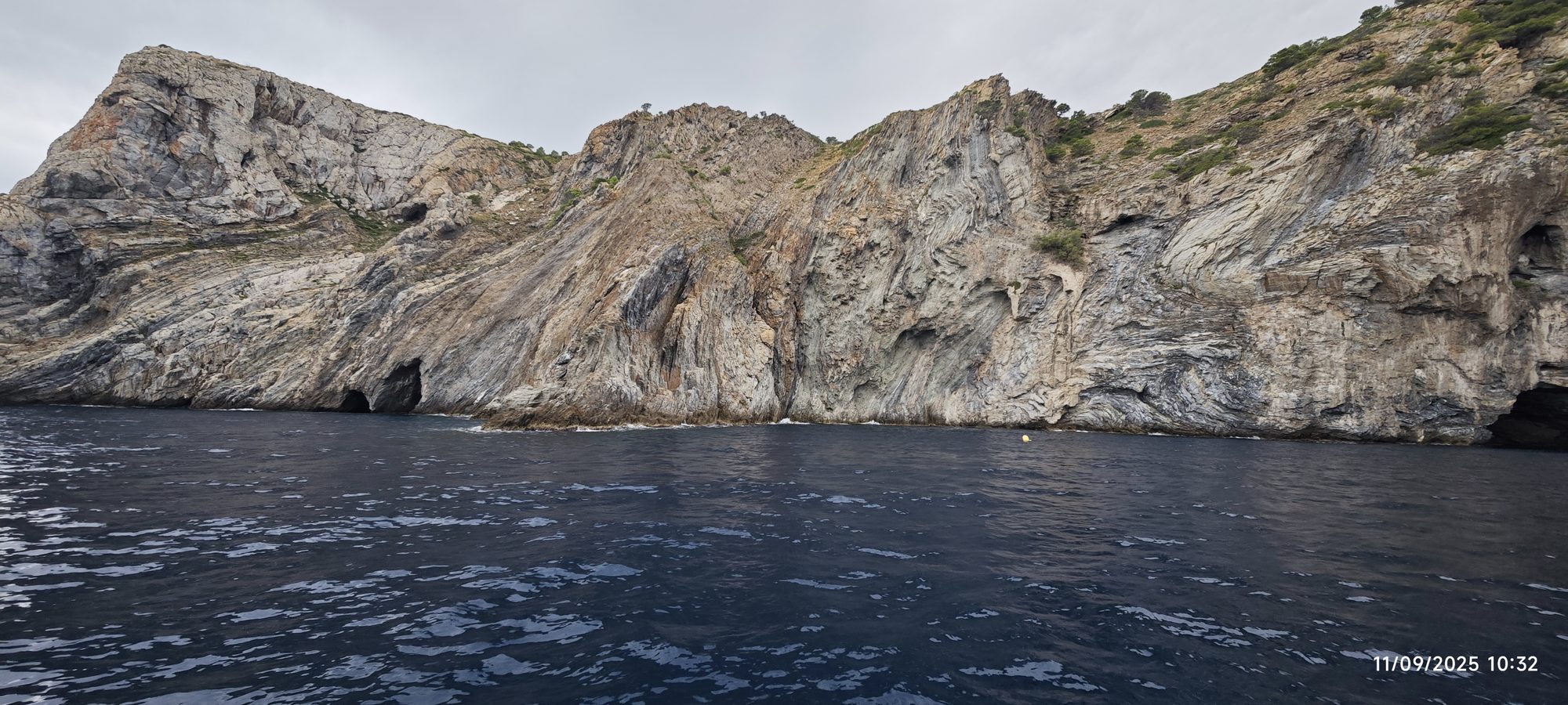 Acantilados rocosos y cuevas marinas frente al mar azul profundo en la costa de Roses.