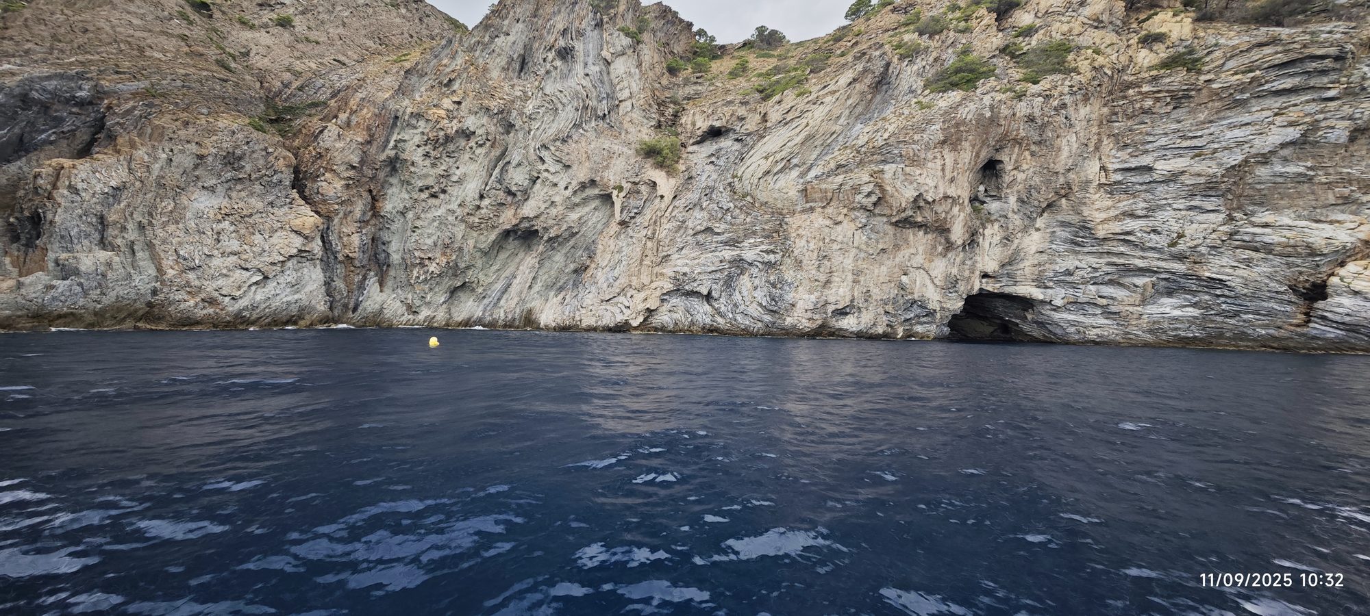 Acantilados rocosos con cueva marina sobre el agua azul del mar.