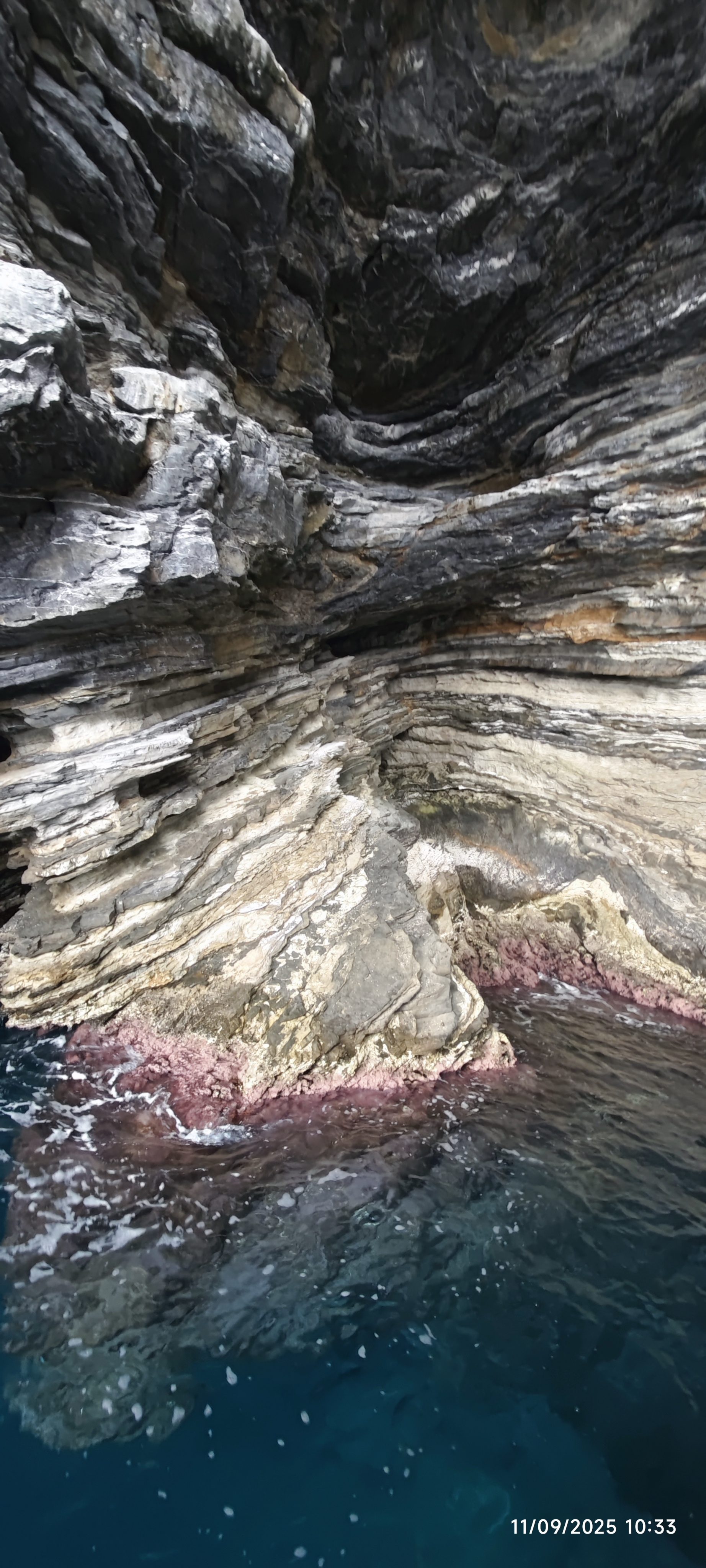 Acantilado rocoso estratificado sobre el agua turquesa del mar en la costa de Begur.